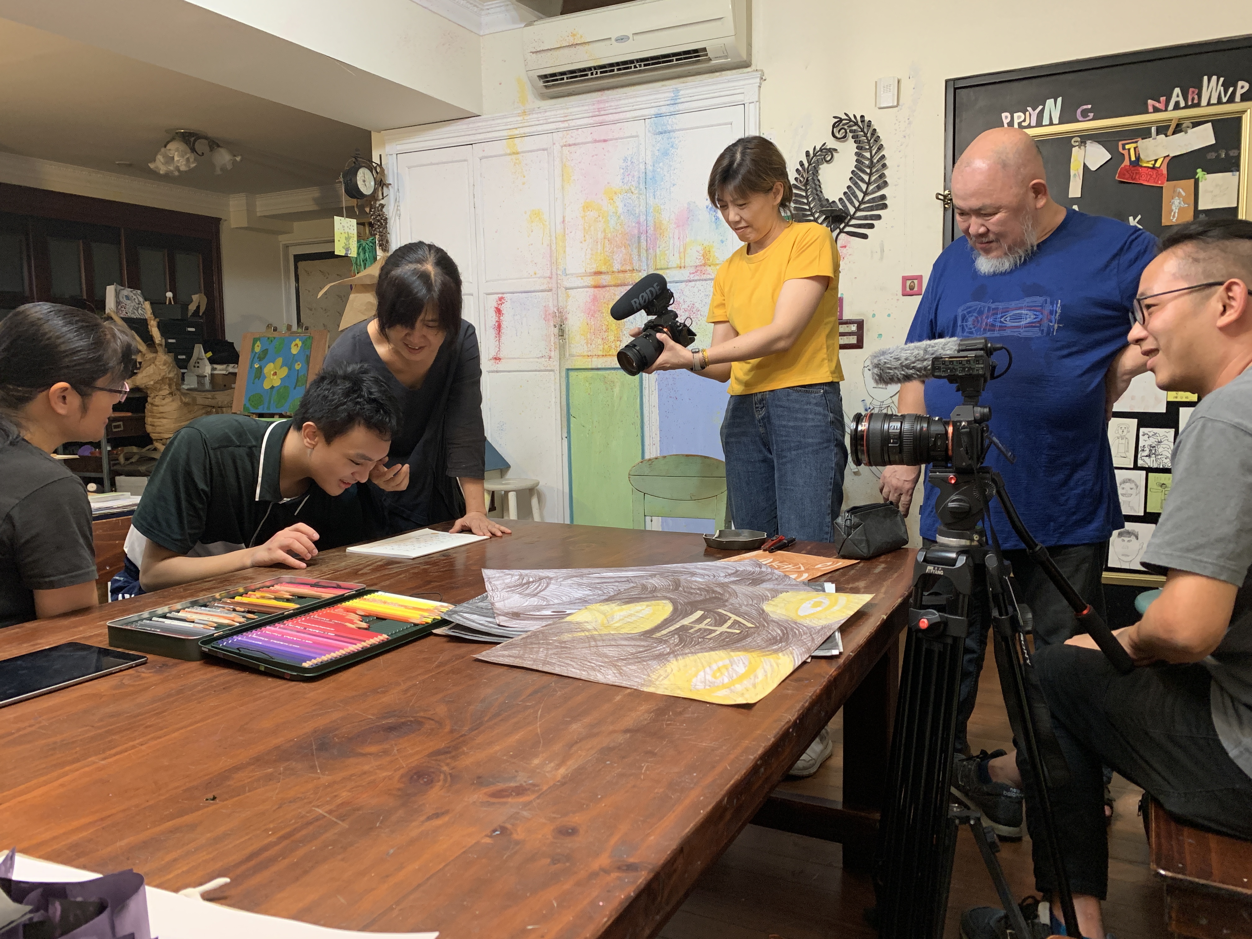 導演林正盛（右二）與年輕班底合作拍攝自閉兒的故事，左三為妻子韓淑華與學員陳藍廷瑋（左二）討論繪畫。（我們之間提供）
