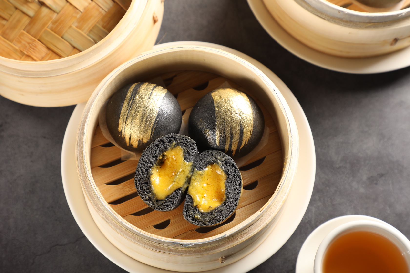 「金箔流沙包」竹炭麵皮刷上食用金粉，呼應內餡濃郁的金沙餡。（150元／份）