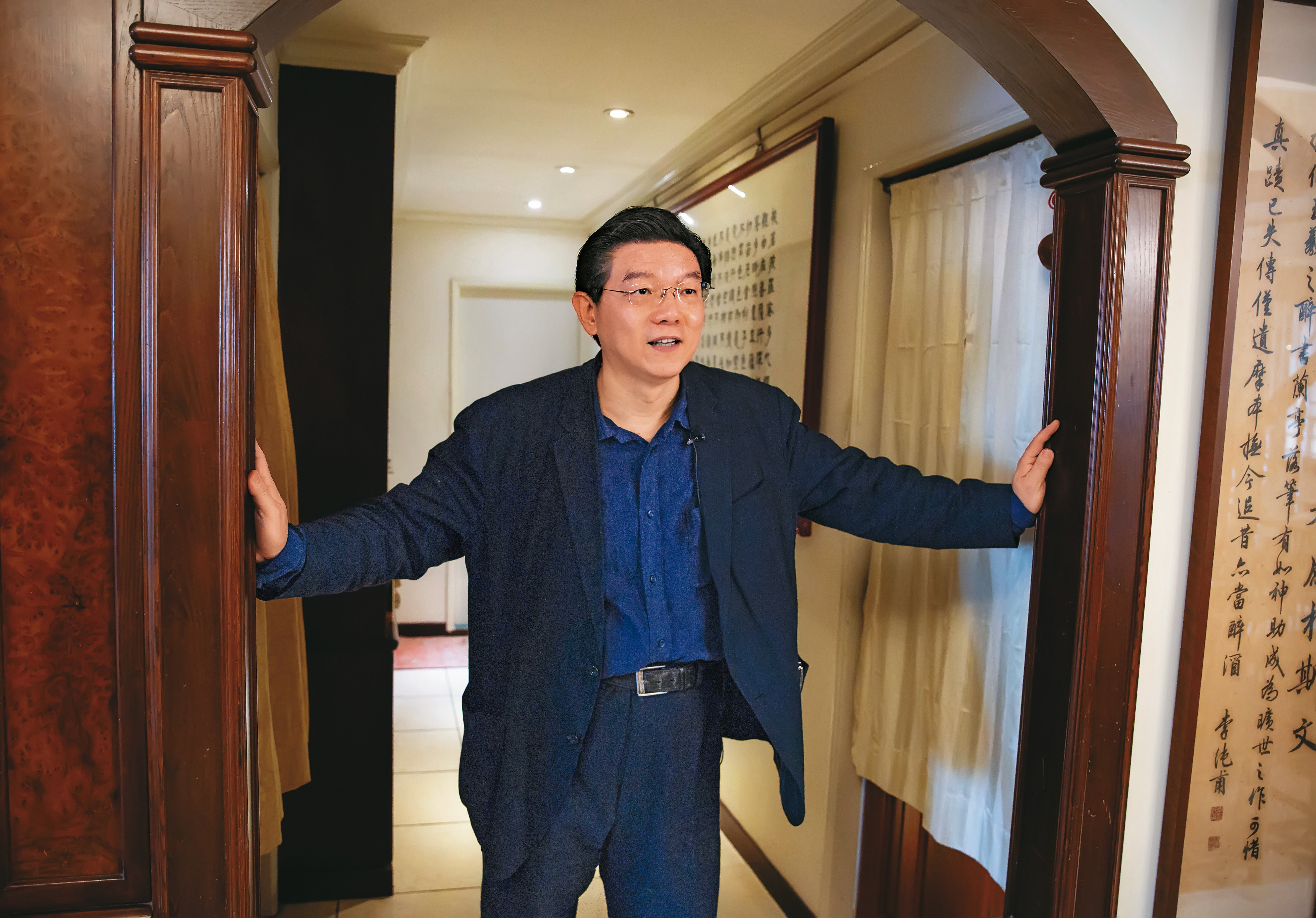 裴偉家的迴廊一邊是塞得滿滿的書櫃，一邊外頭掛著〈心經〉和〈蘭亭集序〉。