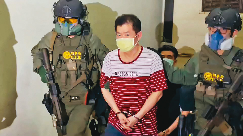 警方荷槍實彈將美鷹會首腦王鑫（中）移送地檢署，王則雙眼狠瞪採訪媒體。