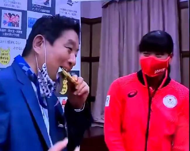 名古屋市長脫下口罩咬選手金牌,引發大批網友怒火。(翻攝推特)