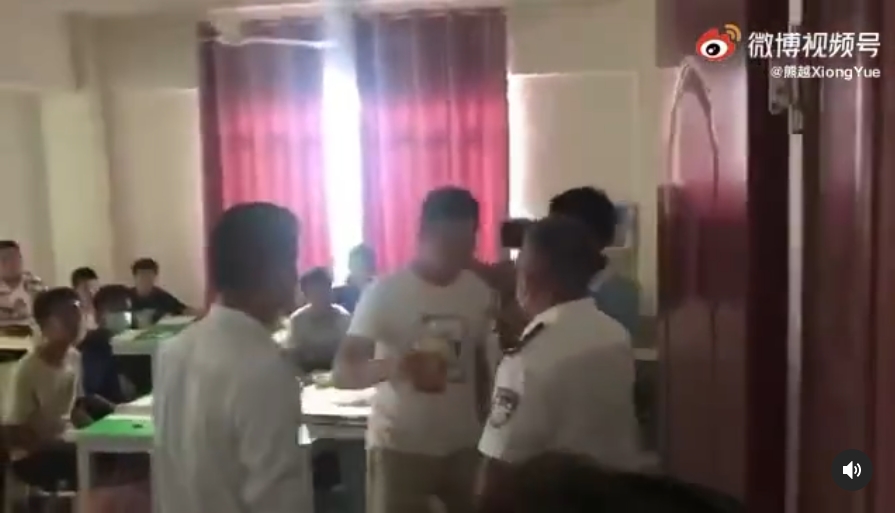 執法人員踹門闖入補習教室，將違規補課的老師掐脖帶出教室。（翻攝自網路）