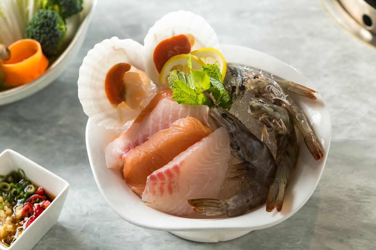 麻辣鍋套餐的綜合海鮮盤裡有鮭魚、鯛魚、白蝦和扇貝。 