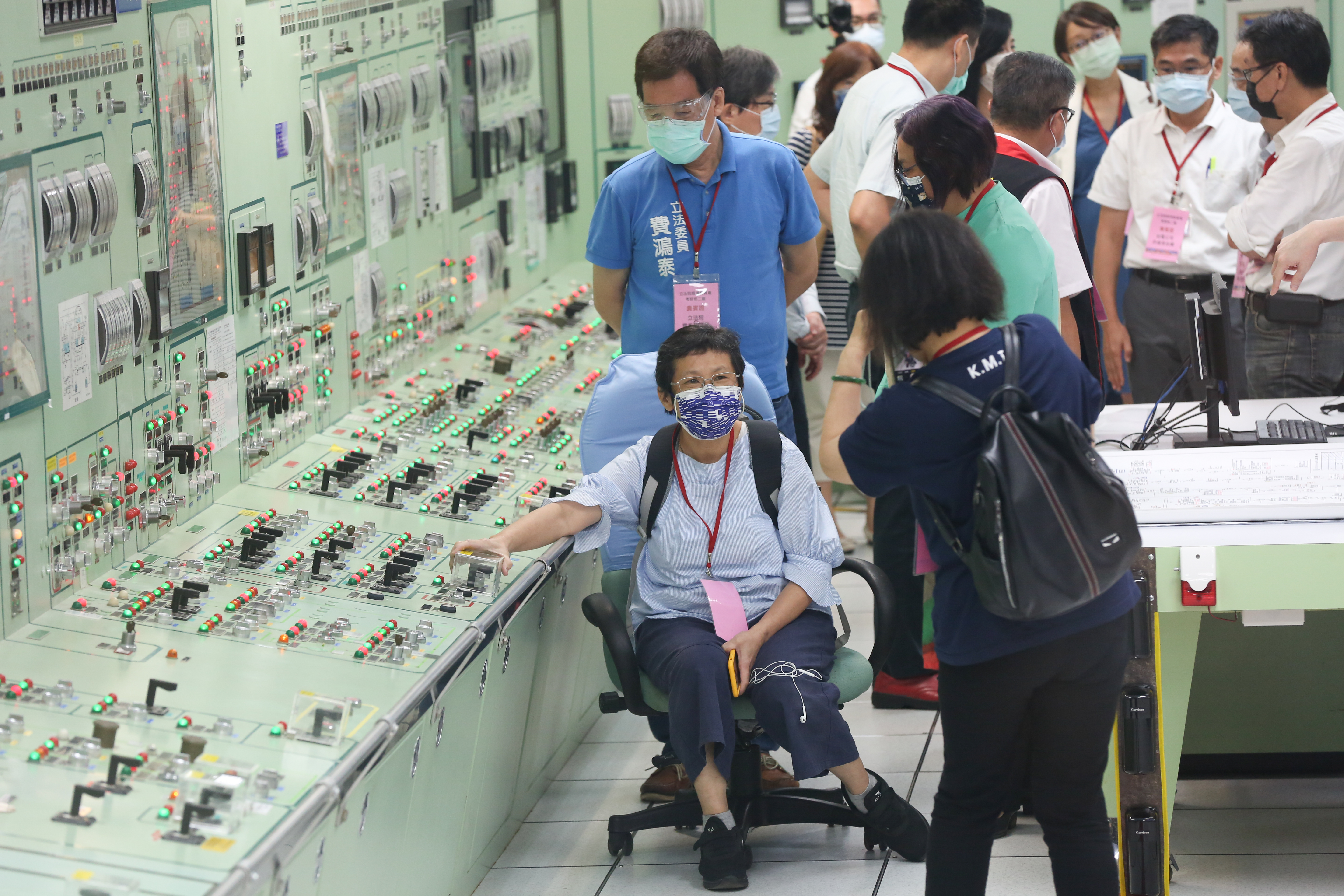 立委陳椒華坐在運轉員椅子上，其右手所握即為開關壓克力保護罩，國民黨立委葉毓蘭在一旁幫她拍照。