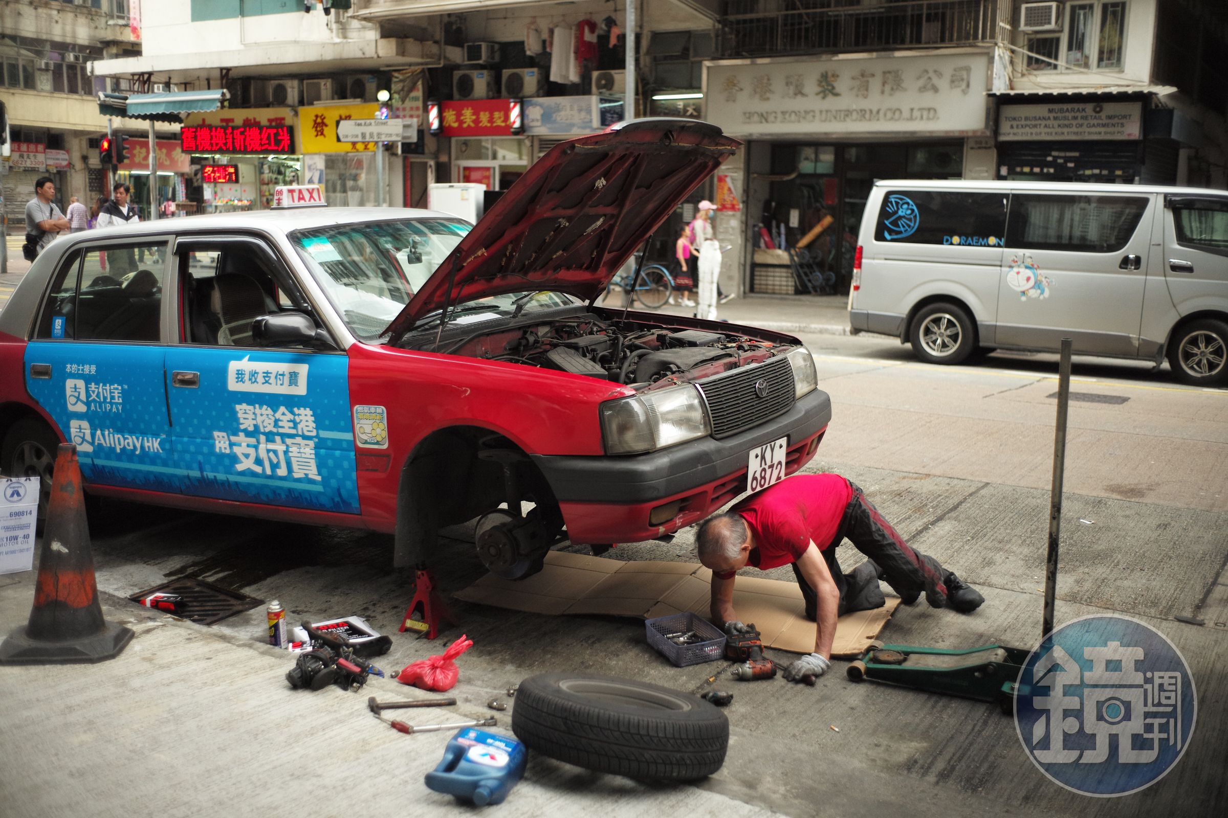 在路邊修理愛車的的士司機。