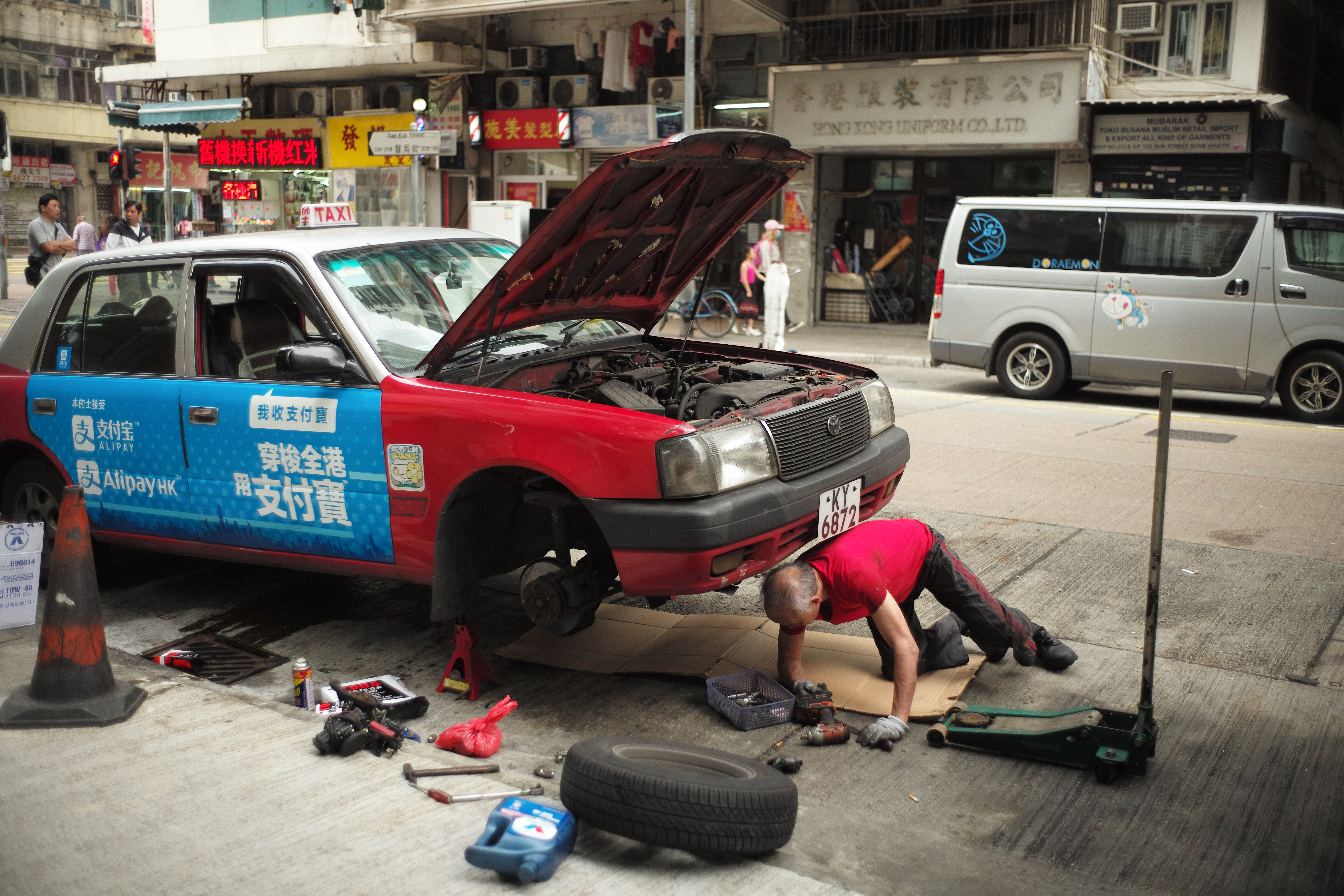 在路邊修理愛車的的士司機。