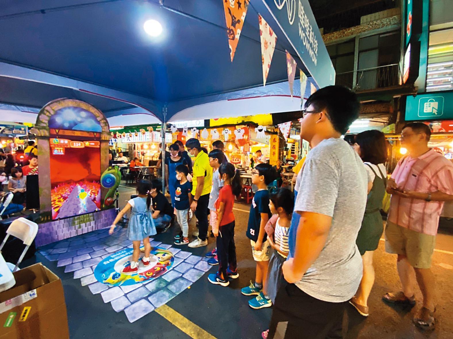 哇哇科技去年將《臺灣妖果》大型機台在高雄六合夜市展出,大批逛街民眾駐足觀看試玩。(翻攝自哇哇科技臉書)