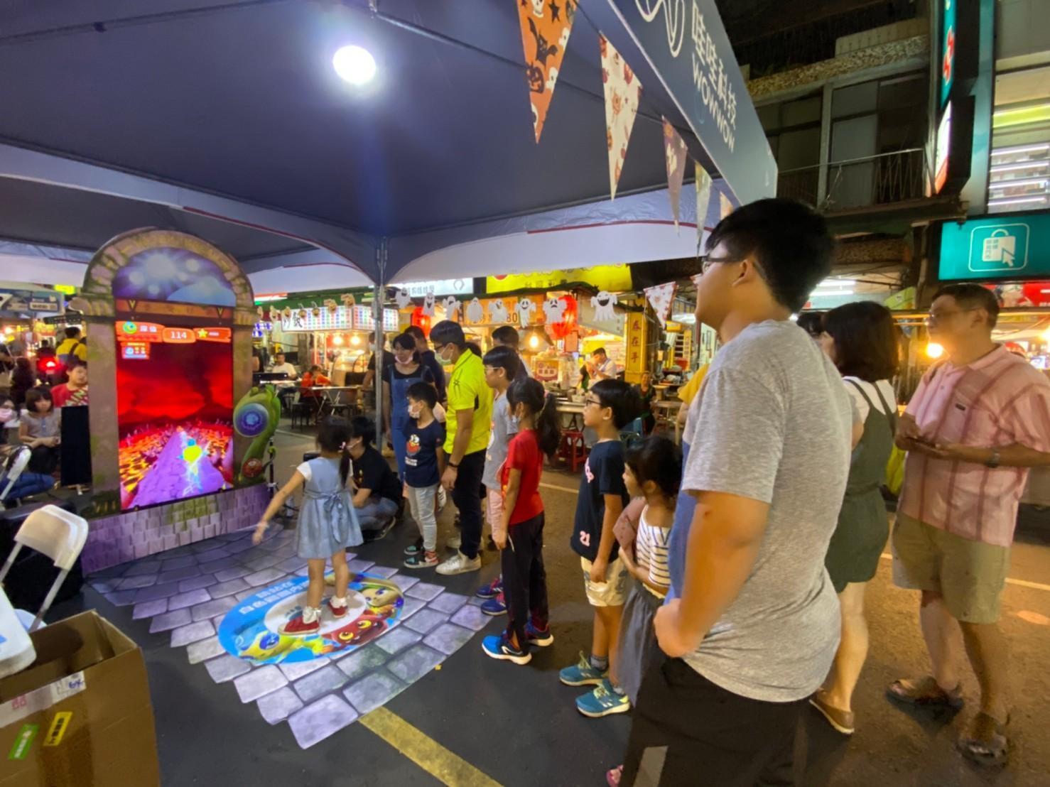 哇哇去年將《妖果小學堂》大型機台在高雄六合夜市展出，大批逛街民眾駐足觀看試玩。（翻攝自哇哇科技FB）