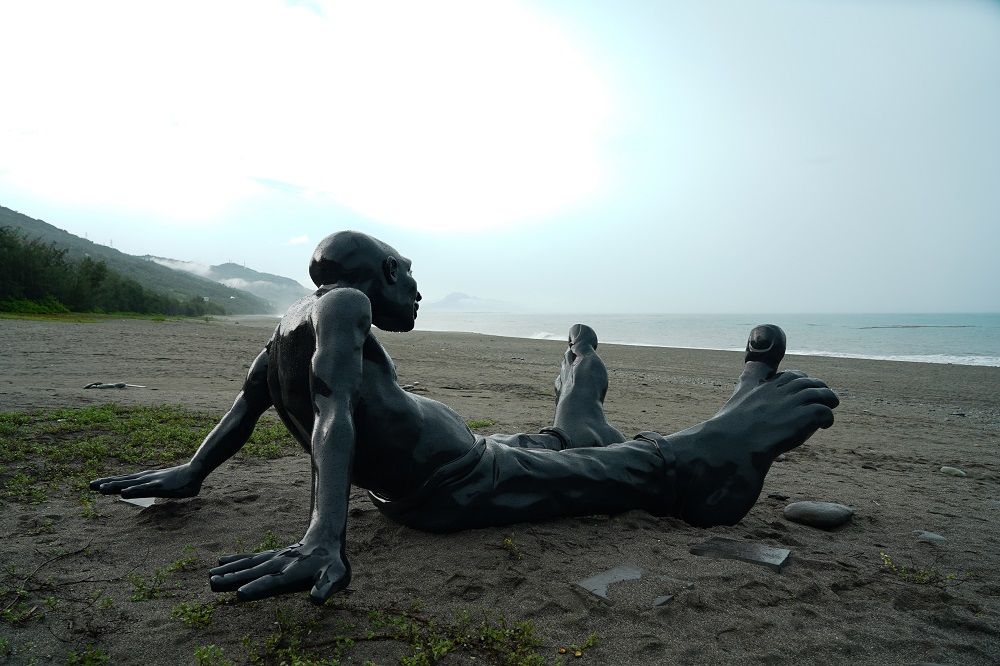 喜歡旅行的以色列藝術家，作品《行走的意識》讓光著腳丫子的巨人悠哉攤坐在海灘、享受海風吹拂。（胡耀仁攝）