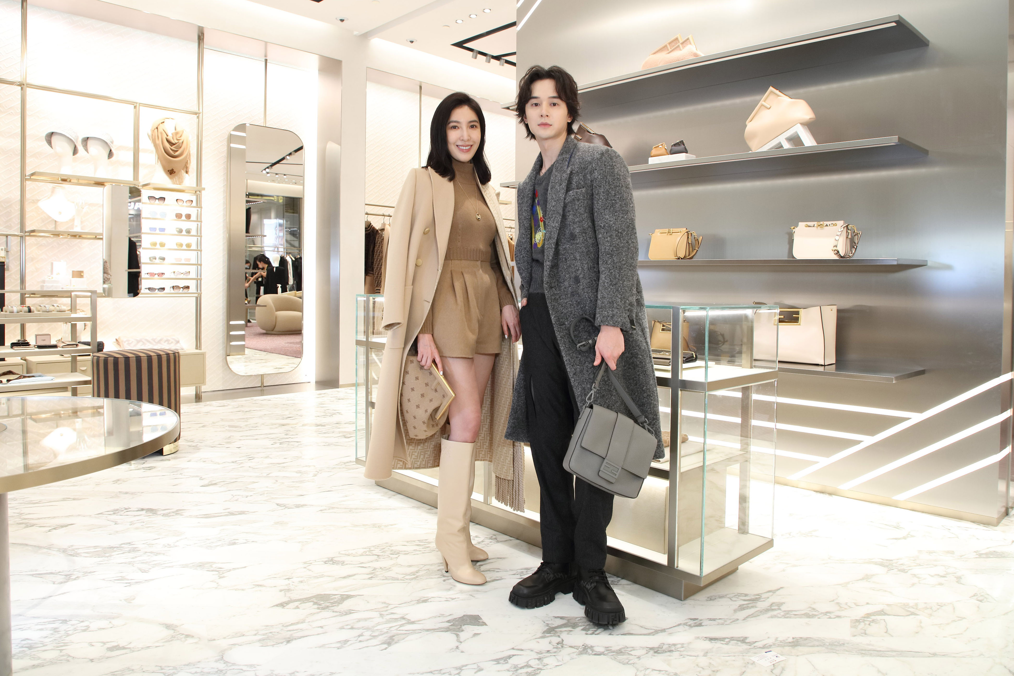 楊謹華打包帶回身上的大衣NT$132,000；她穿著高領羊毛短版上衣NT$34,900、高腰造型羊毛短褲NT$28,700、高跟長靴NT$51,000、First系列Karligraphy圖騰包款(中)NT$106,000。張軒睿因為NT$148,000的灰色羊毛大衣保暖十足而滿身大汗，他身著塗鴉造型羊毛背心NT$32,900、Vertigo系列長褲NT$24,500、大象灰Baguette Messenger包款NT$86,000。（FENDI提供）