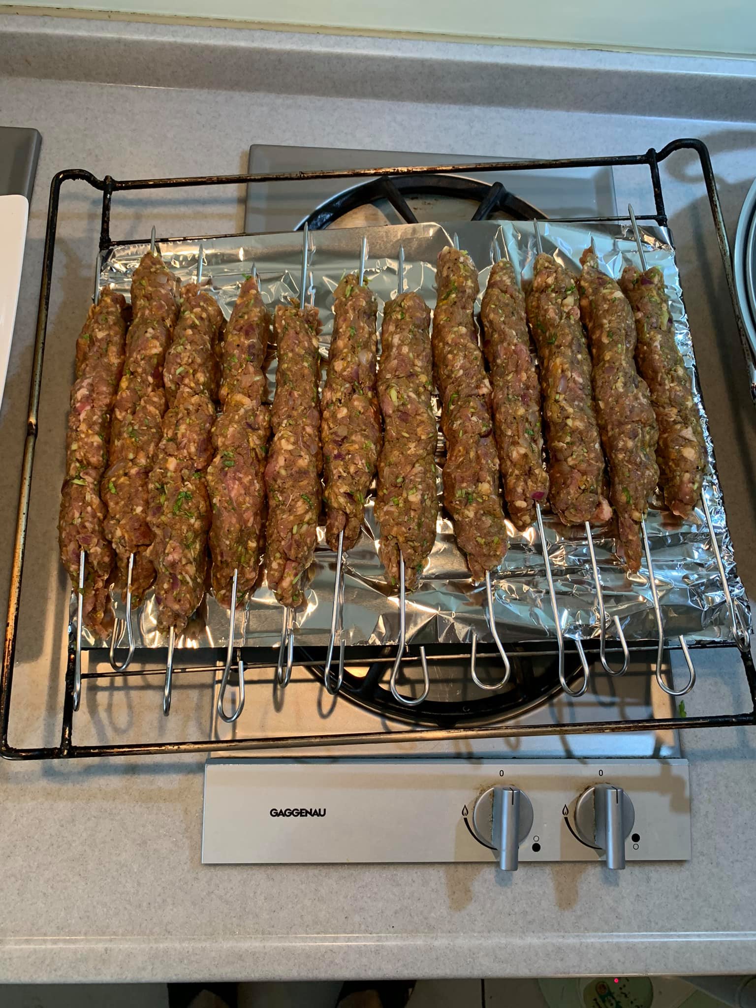 把捏好的肉串放在烤架上。