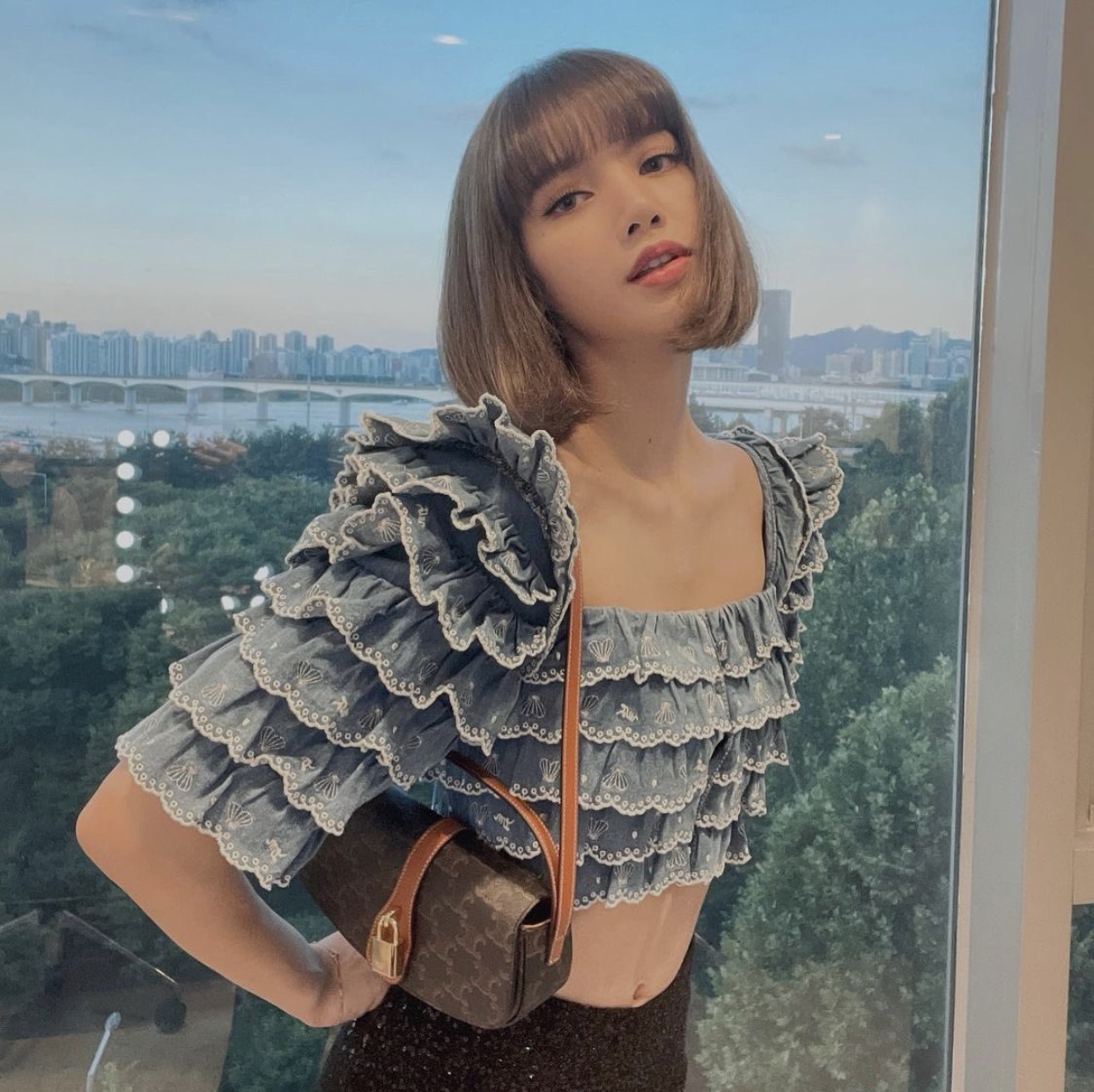 LISA穿著可愛又性感的短版蛋糕上衣，搭配CELINE經典老花帆布Tabou Clutch。