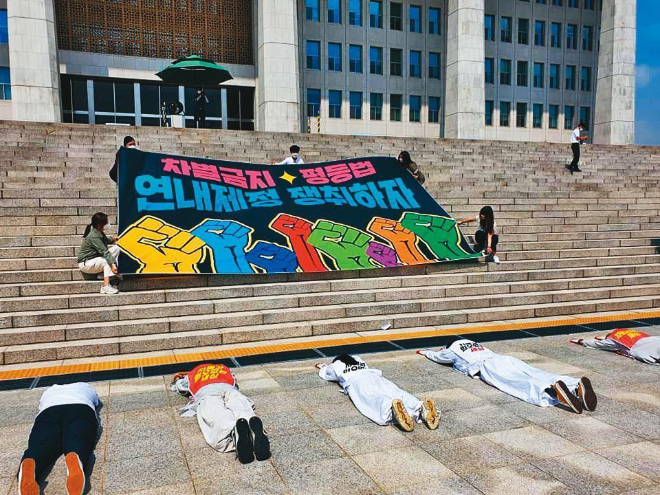 在南韓國會議場的正門階梯上，一群社運人士拉起大布條，要求「爭取在年內制定禁止歧視‧平等法」。（《禁止歧視法》制訂聯盟提供）