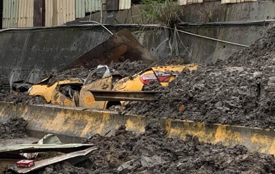 砂石廠房牆面崩塌,一輛路過的計程車遭到大量土石活埋。(翻攝畫面)