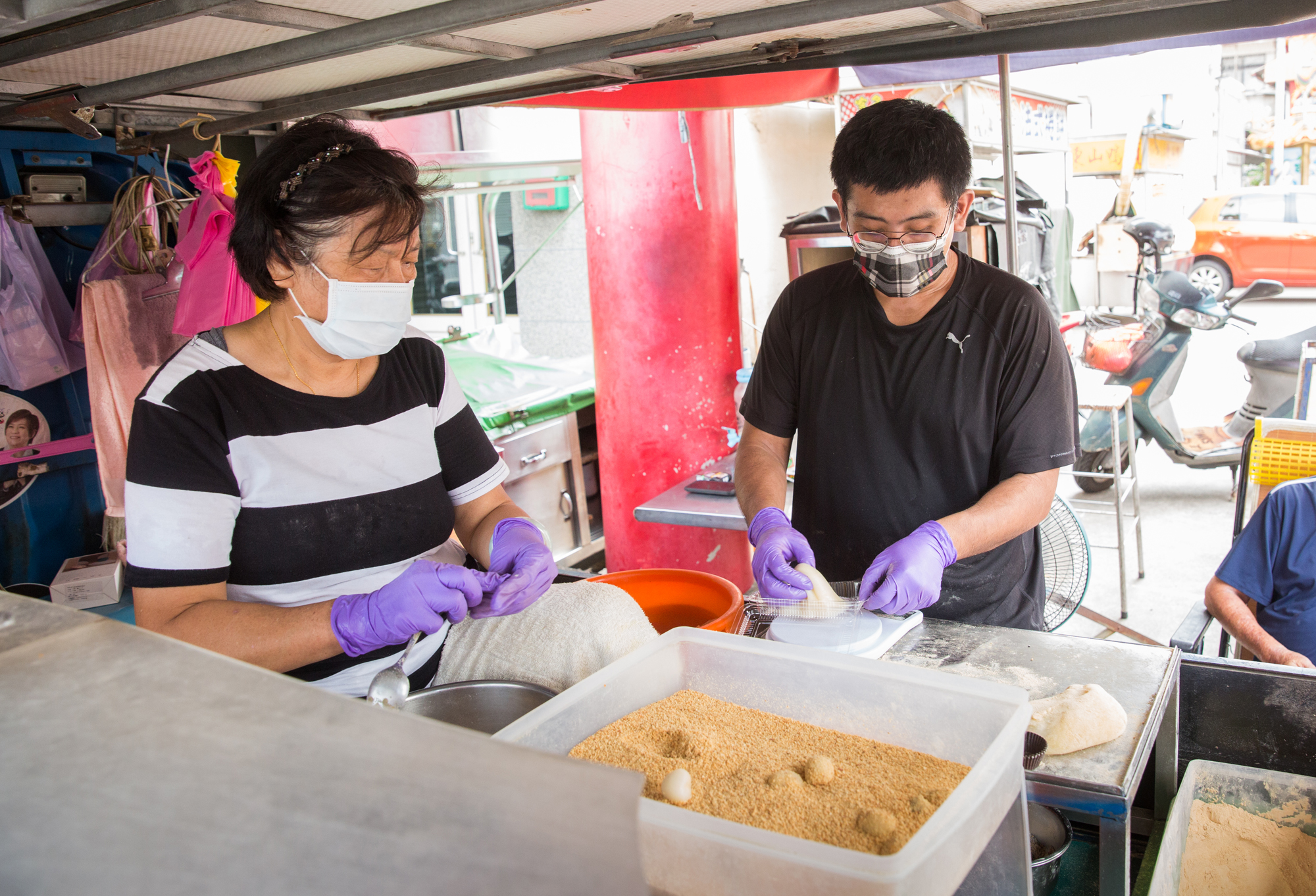 擺攤時母子2人延續從第一代開始的作業動線，施建旭（右）站在車子旁、王秋雙（左）坐在車斗，分工合作製作麻糬。