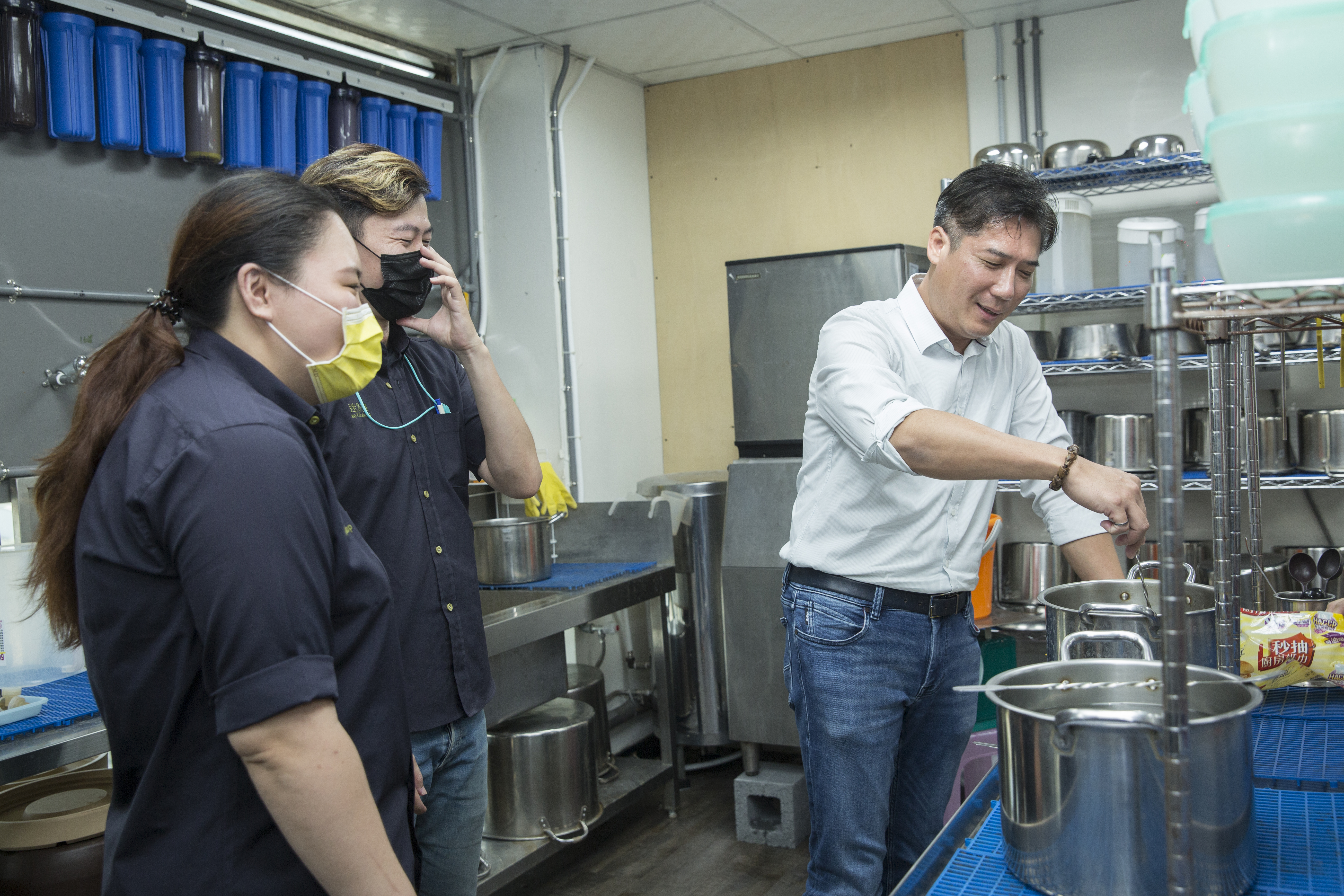 參與迷客夏飲料研發的林建燁（右），喜歡待在後場煮茶。圖為林建燁在總部親自示範迷客夏員工必學的「攪水」，能讓茶葉吃水更均勻。