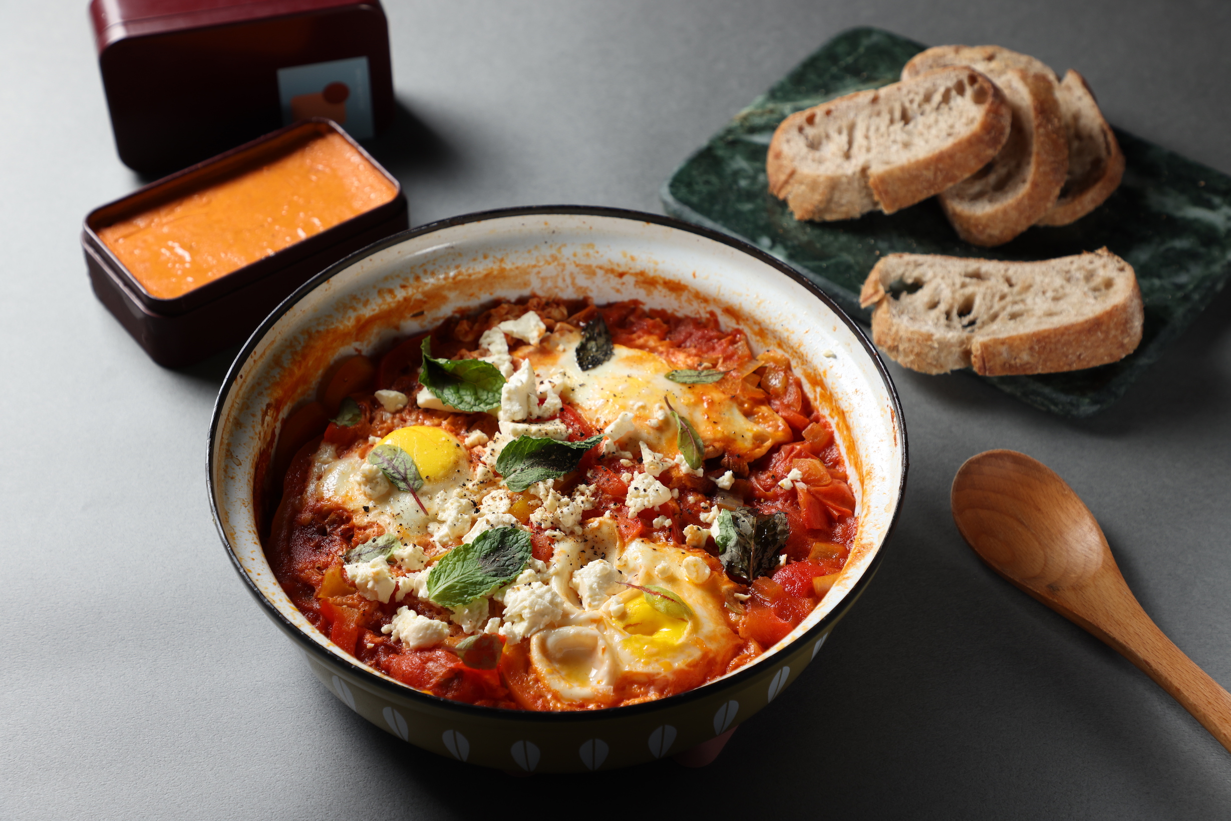 使用「油封香料番茄」與「微辣奶油」製作的「沙卡蔬卡Shakshuka」燉蛋料理，搭配麵包辛香暖胃。