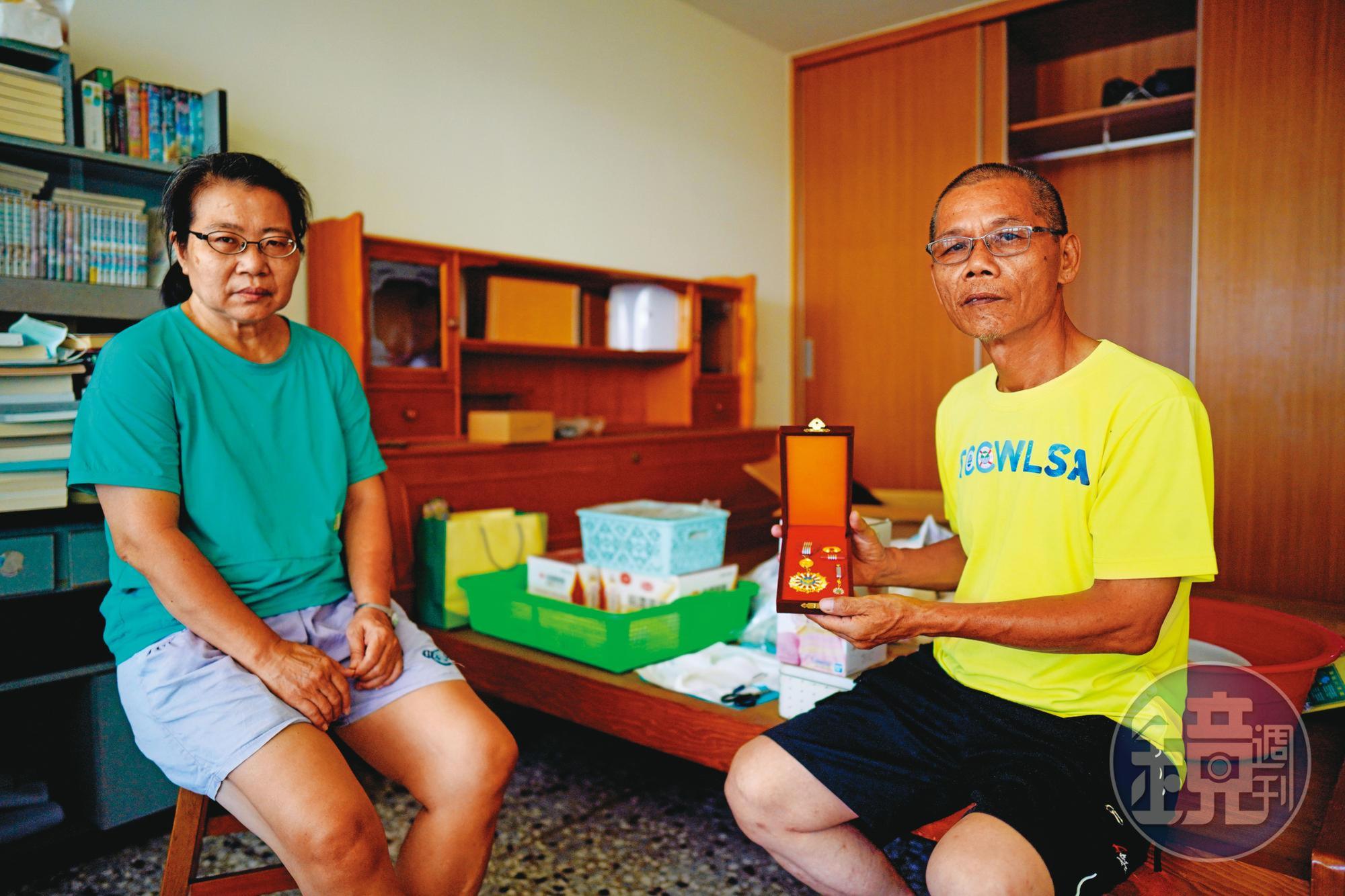 母親梁春子（左）、父親陳貴森（右）拿著勳章在陳志帆房間拍照，母親強忍悲傷，一度說不想拍了。（林韋言攝）