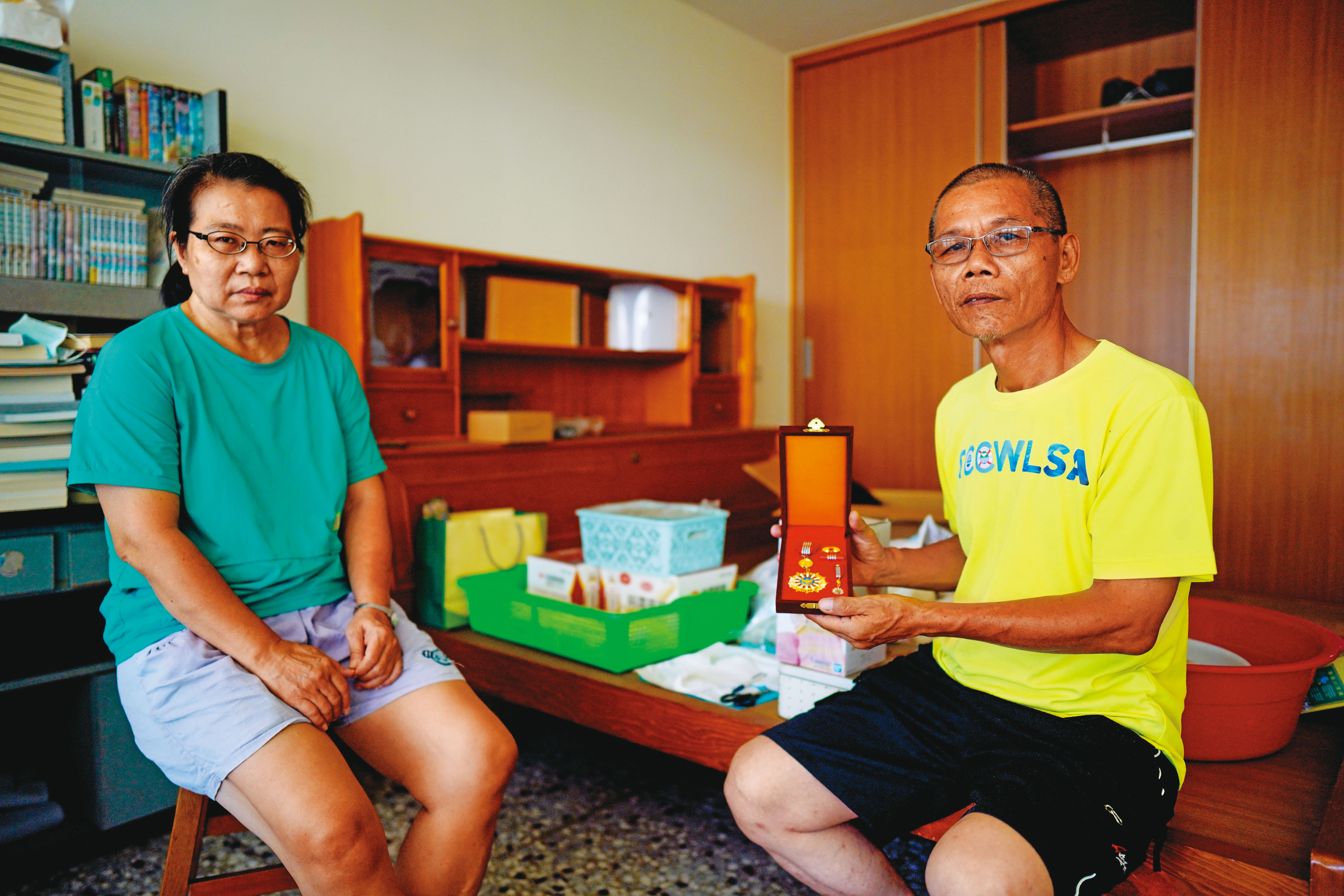 母親梁春子（左）、父親陳貴森（右）拿著勳章在陳志帆房間拍照，母親強忍悲傷，一度說不想拍了。（林韋言攝）