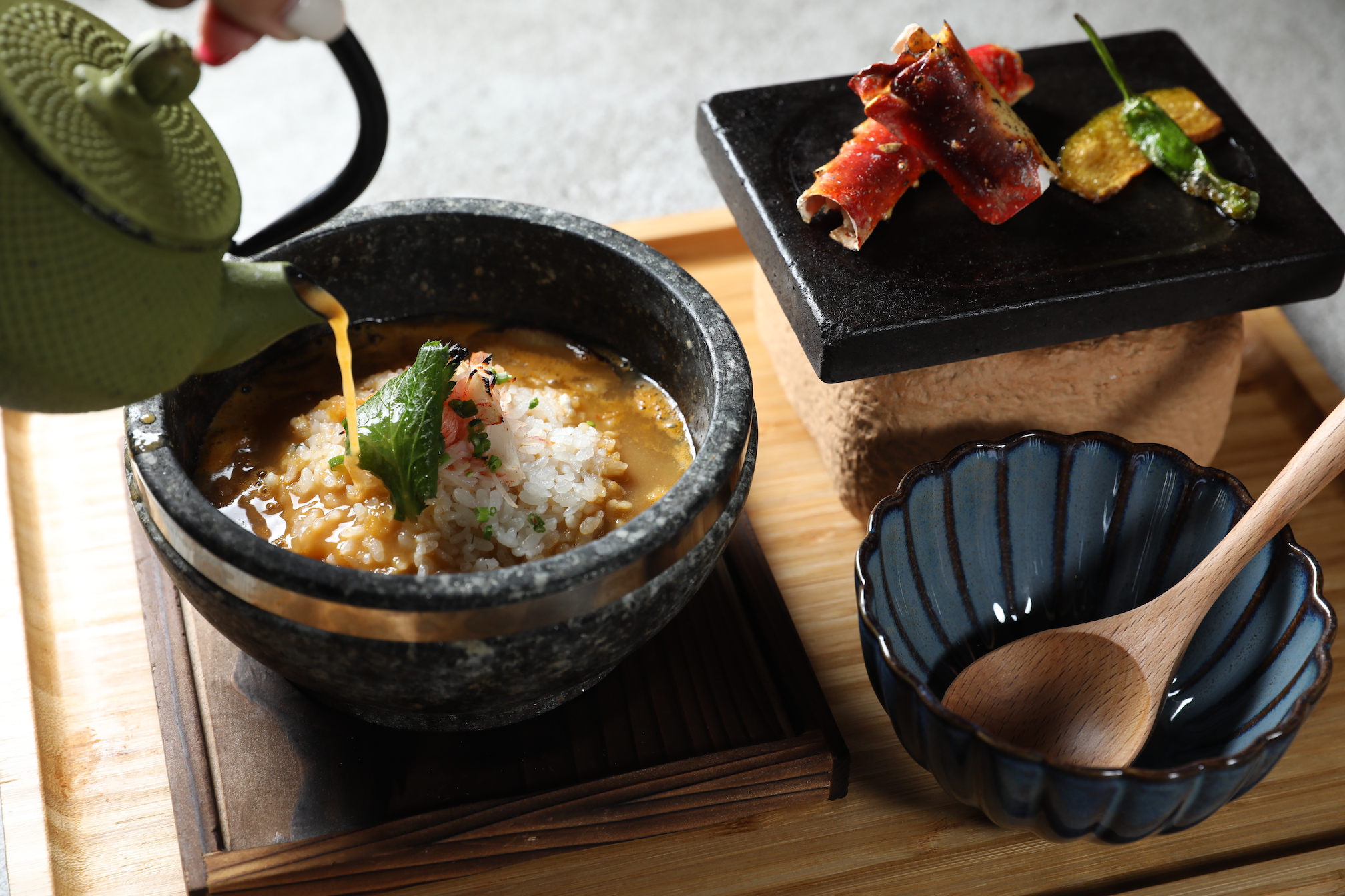 「岩燒鱈場蟹石鍋泡飯」以燉煮6小時的濃郁紅蝦湯頭倒入燒熱的岩石鍋飯，搭配鱈場蟹肉。（380元／份）