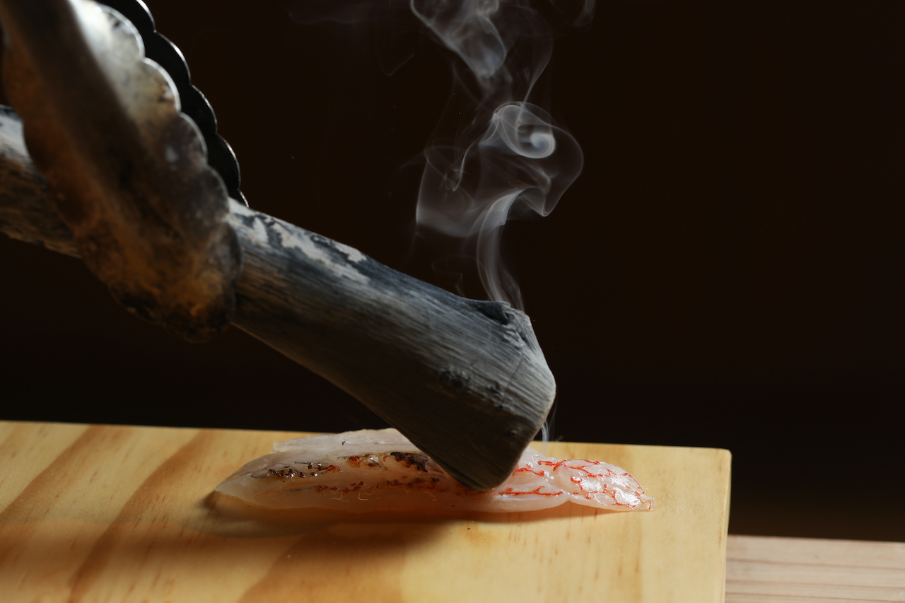 以炭火炙烤魚鮮，煙氣啓動人們感官，炒熱用餐氣氛。