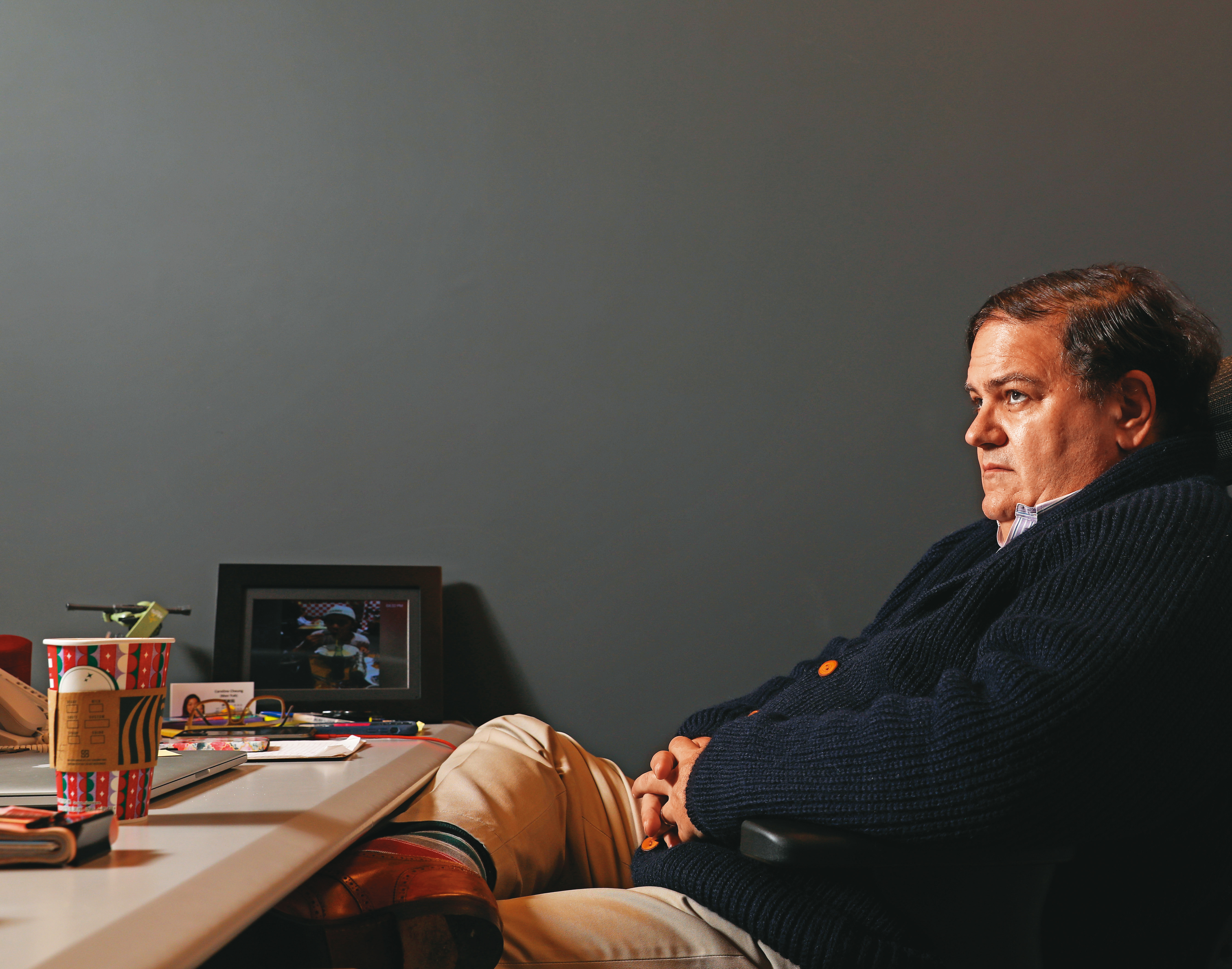 馬克．賽門近日為台灣《蘋果》出售案感到焦慮。圖為他在台灣辦公室內，桌上數位相框輪播著他家人與黎智英的照片。