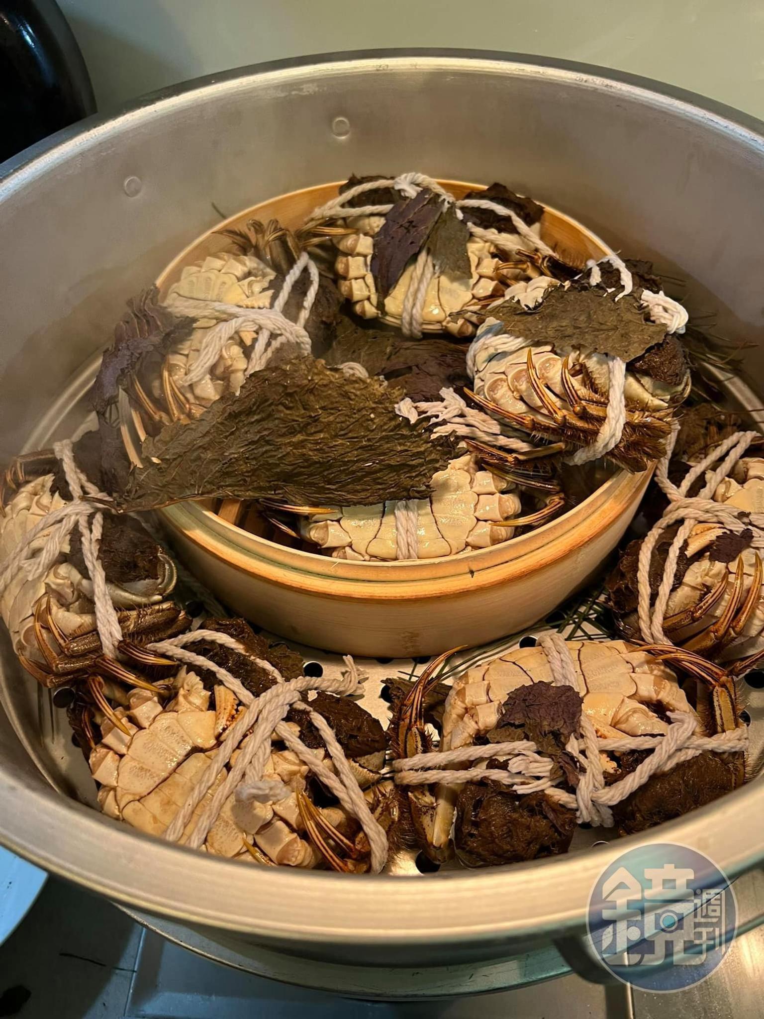 移走紫蘇葉，將蒸到剛好的大閘蟹取出。
