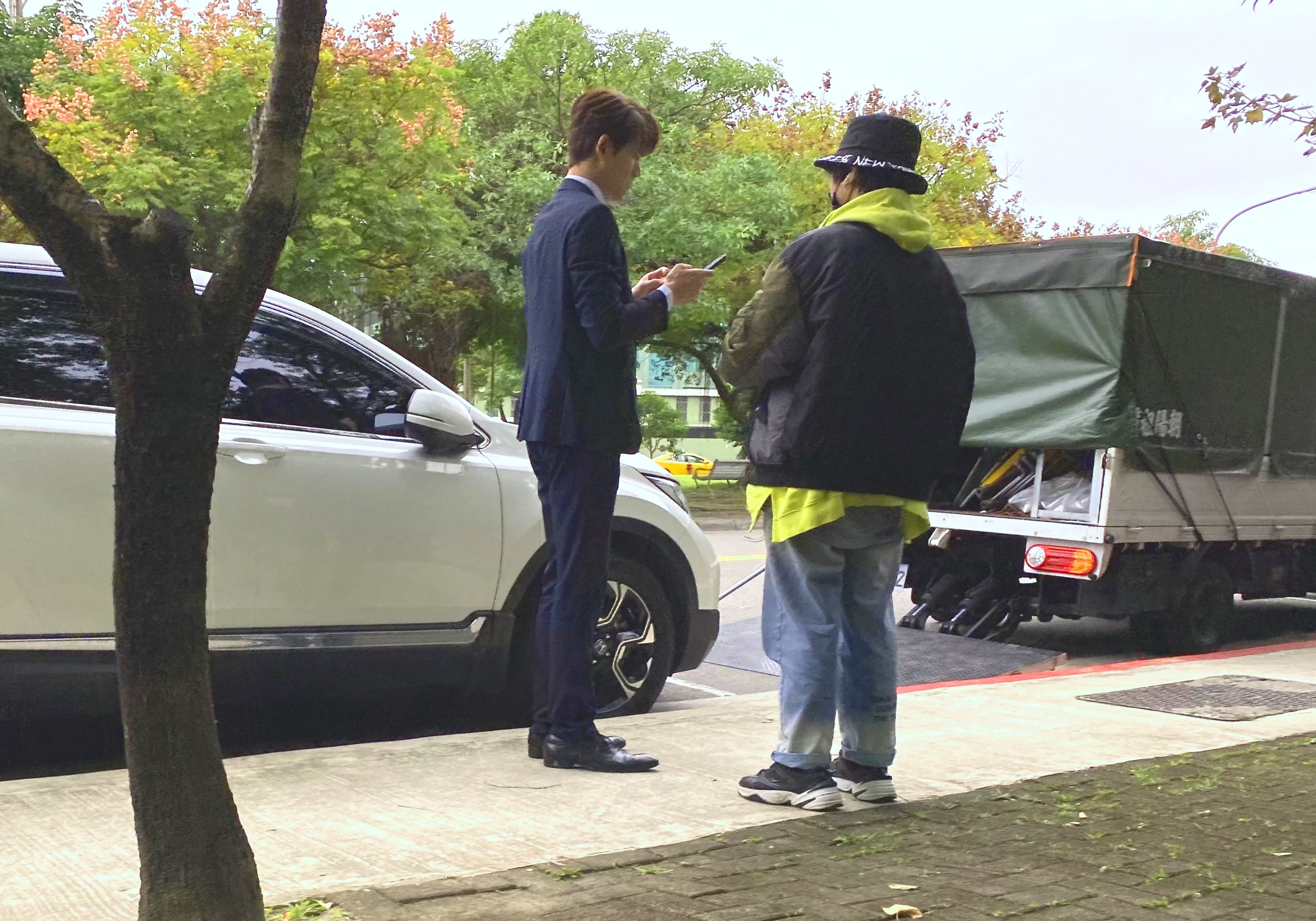 余秉諺日前在台北市內湖路邊拍三立八點檔《天之驕女》，利用空檔在一旁忙碌滑手機。（讀者提供）