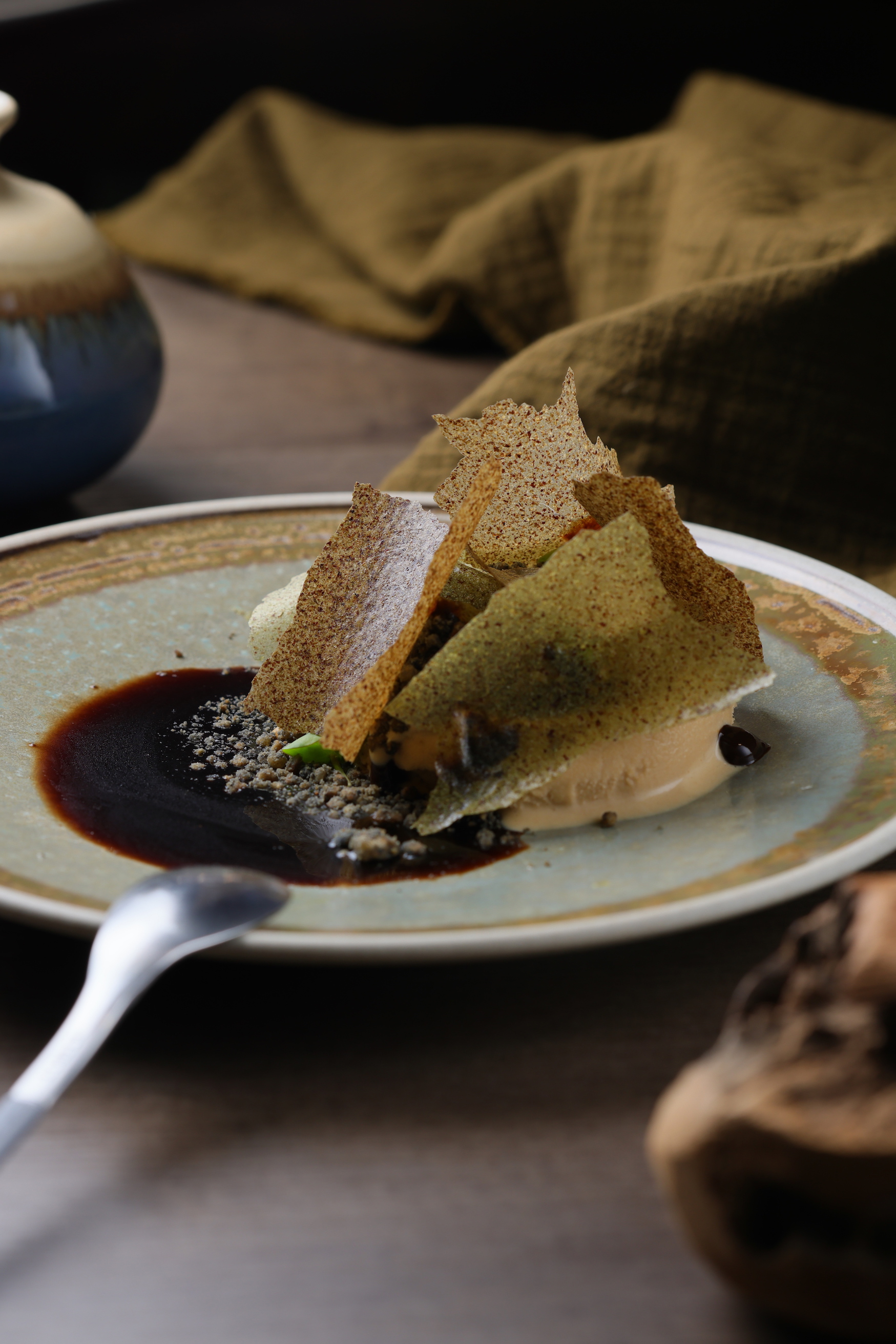 「大地」以麵茶清酒黑糖冰為底，加上竹炭奶酥、松針藜麥脆片與黑蒜葡萄酒醋醬，隱約有牛肝蕈的氣息。