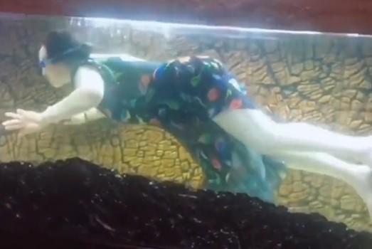 中國一位大媽在自家客廳魚缸裡潛水撈魚，影片引發討論。（翻攝自微博）