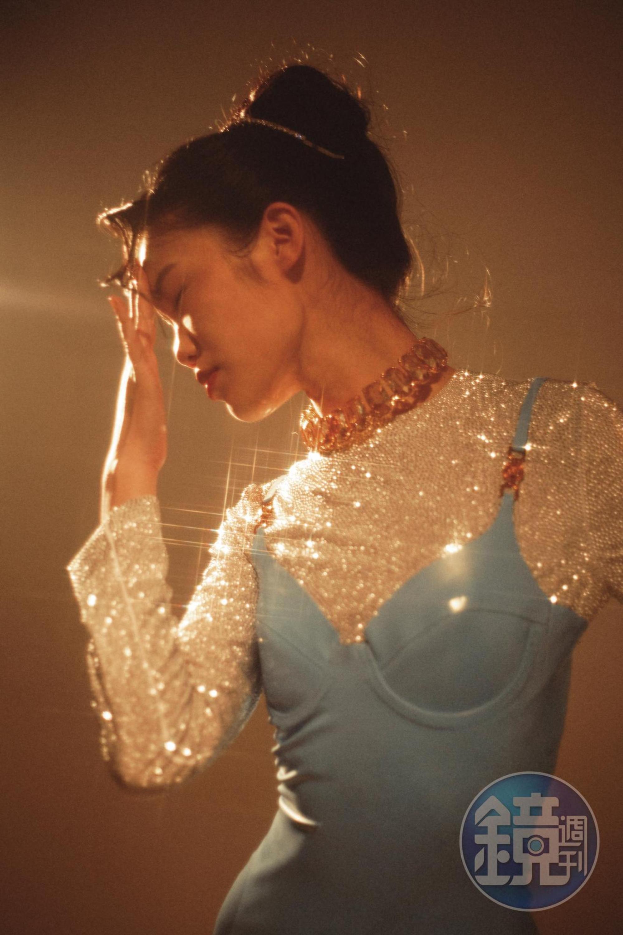 水藍色細肩乳膠洋裝 NT$74,500 by VERSACE；水晶墜飾短版上衣 NT$105,000 by MIU MIU；水晶綴飾頭箍 價格店洽 by MIU MIU；Harmonia水晶項鍊 NT$32,900 by SWAROVSKI。