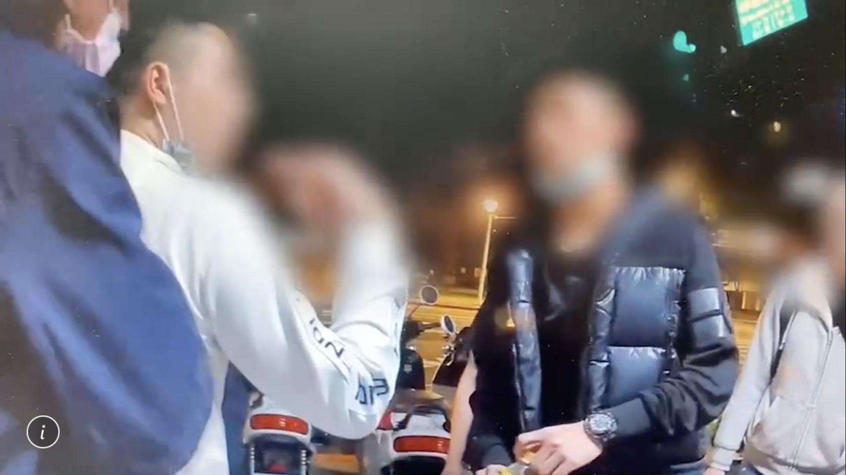 吳男（白衣者）酒醉揮拳打人遭裁罰，事後在警局前與警員發生口角。（翻攝畫面）