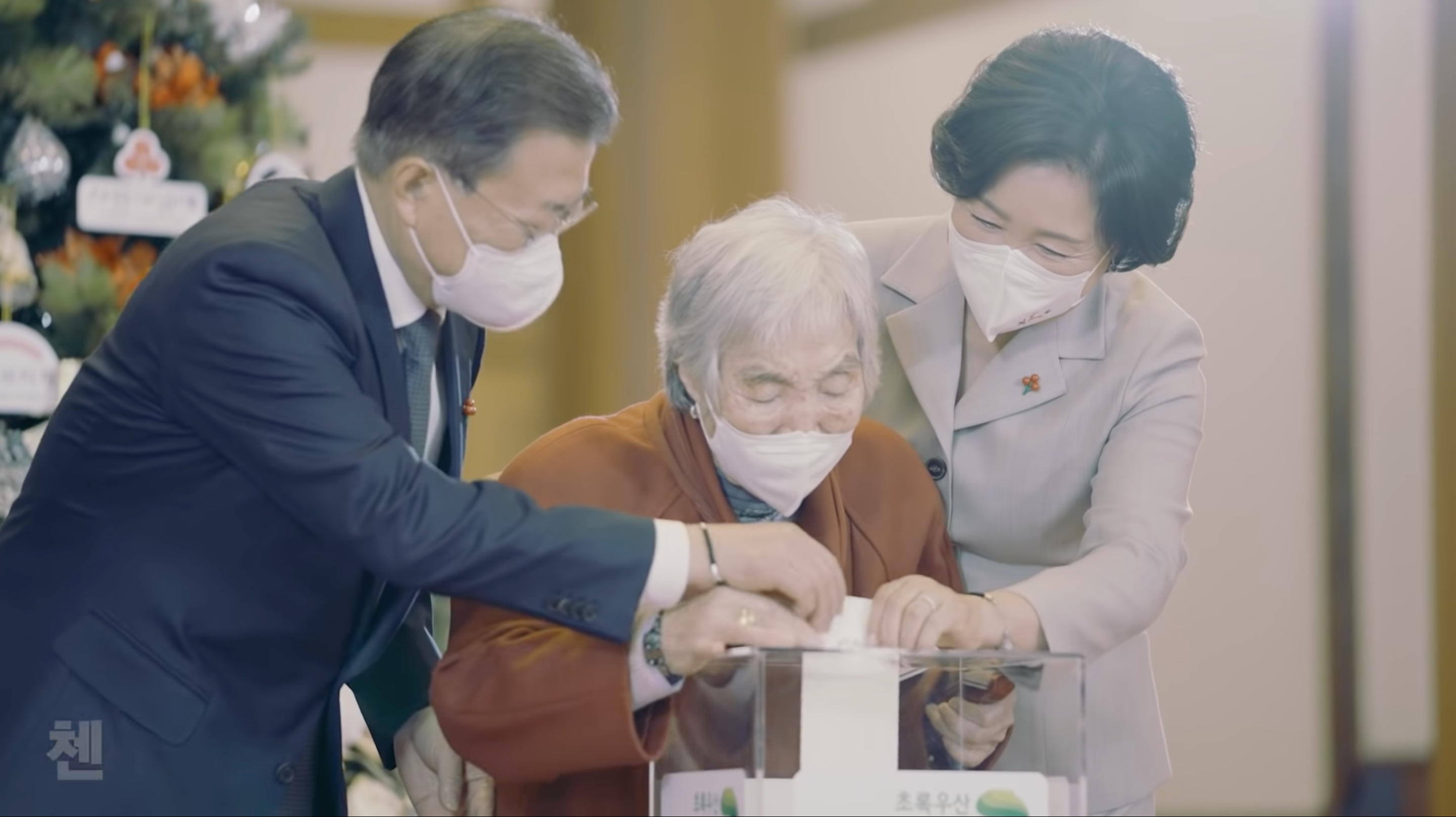 南韓一名販售紫菜包飯維生的奶奶朴春子（中），共捐出了1,500萬元善款，上個月更前往青瓦台接受總統文在寅（左）和第一夫人金正淑（右）的表揚。（翻攝自大韓民國青瓦台YouTube）