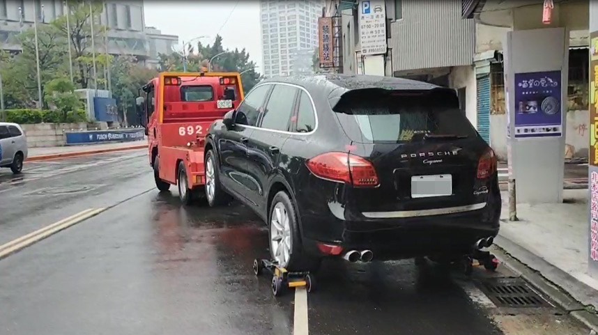 新北分署執行人員在新莊區路邊收費停車格查封許姓男子的保時捷，準備拖吊回保管場。（翻攝畫面）