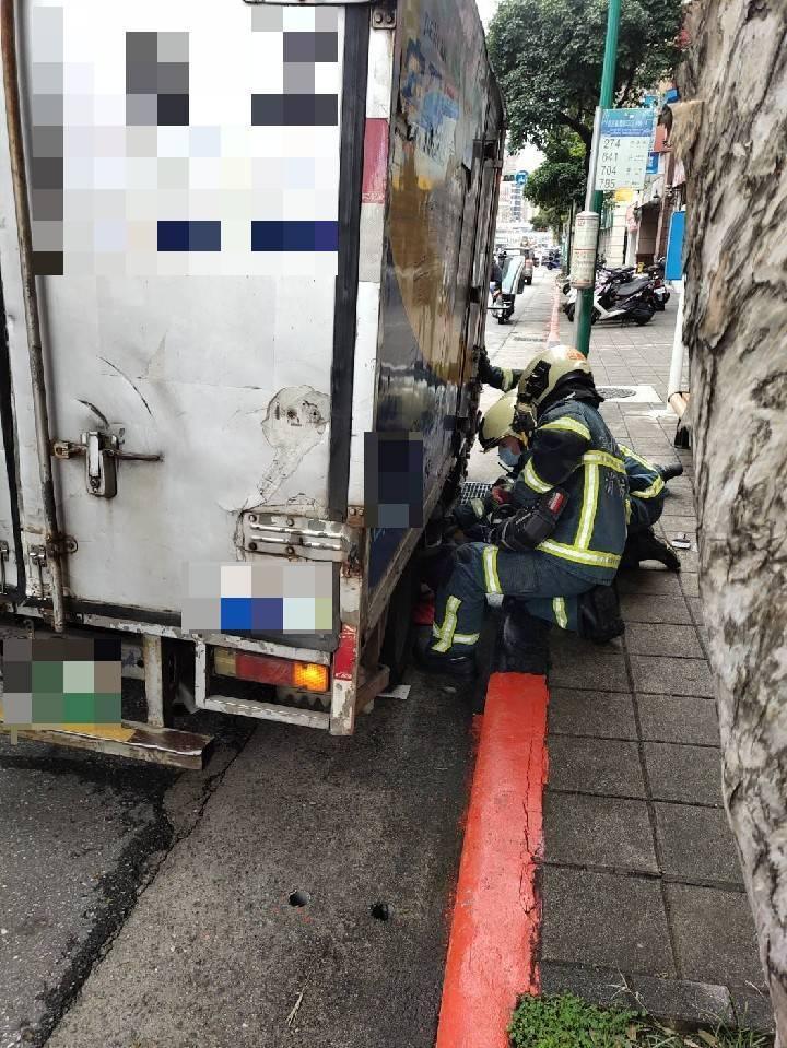 消防人員彎腰到車底要救阿嬤。(警方提供)