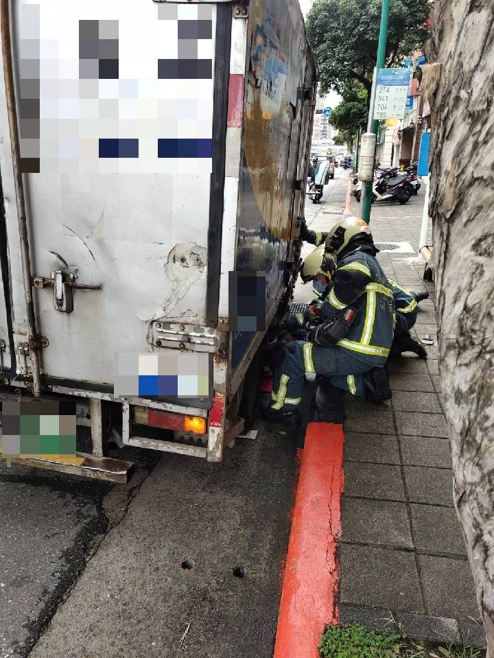 消防人員彎腰到車底要救阿嬤。（警方提供）