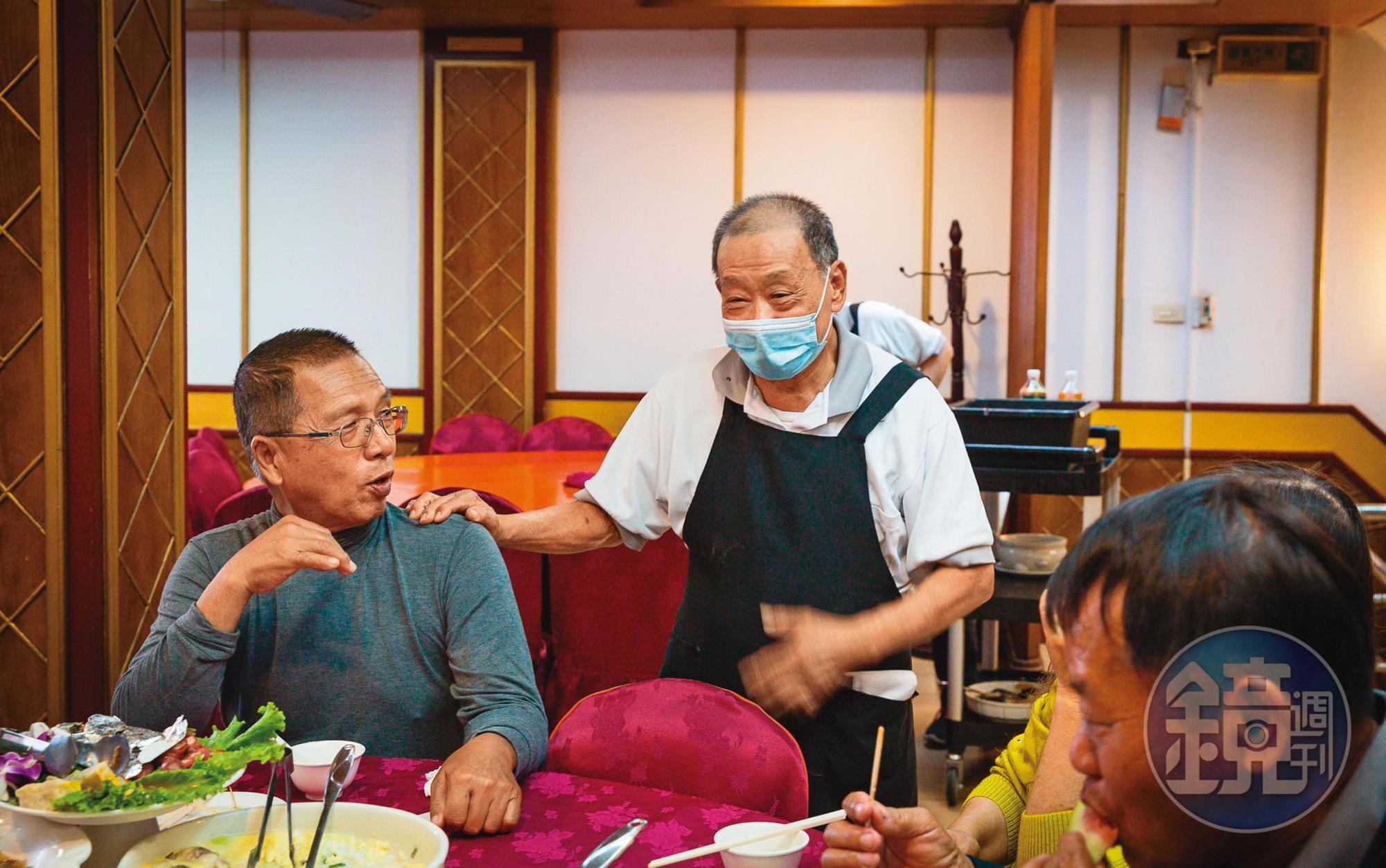 吳火塗(右)燒完菜後,常到桌邊與客人閒話家常,男女老幼都能聊上二句。