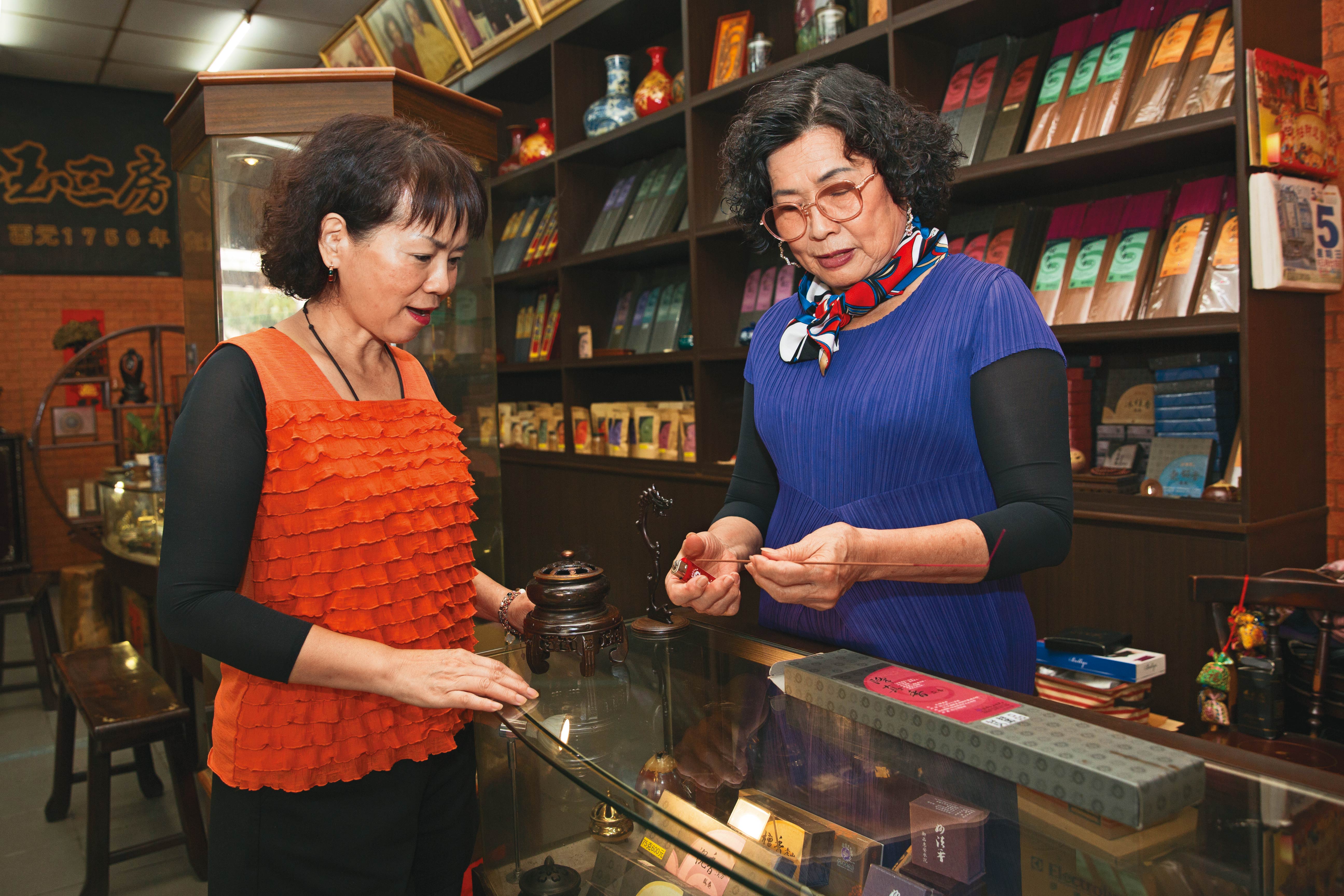 只要客人進店,第7代老闆娘洪寶真(右)一定點香讓客人試聞,詳細解釋何謂中藥養生香。左為顧客林小姐