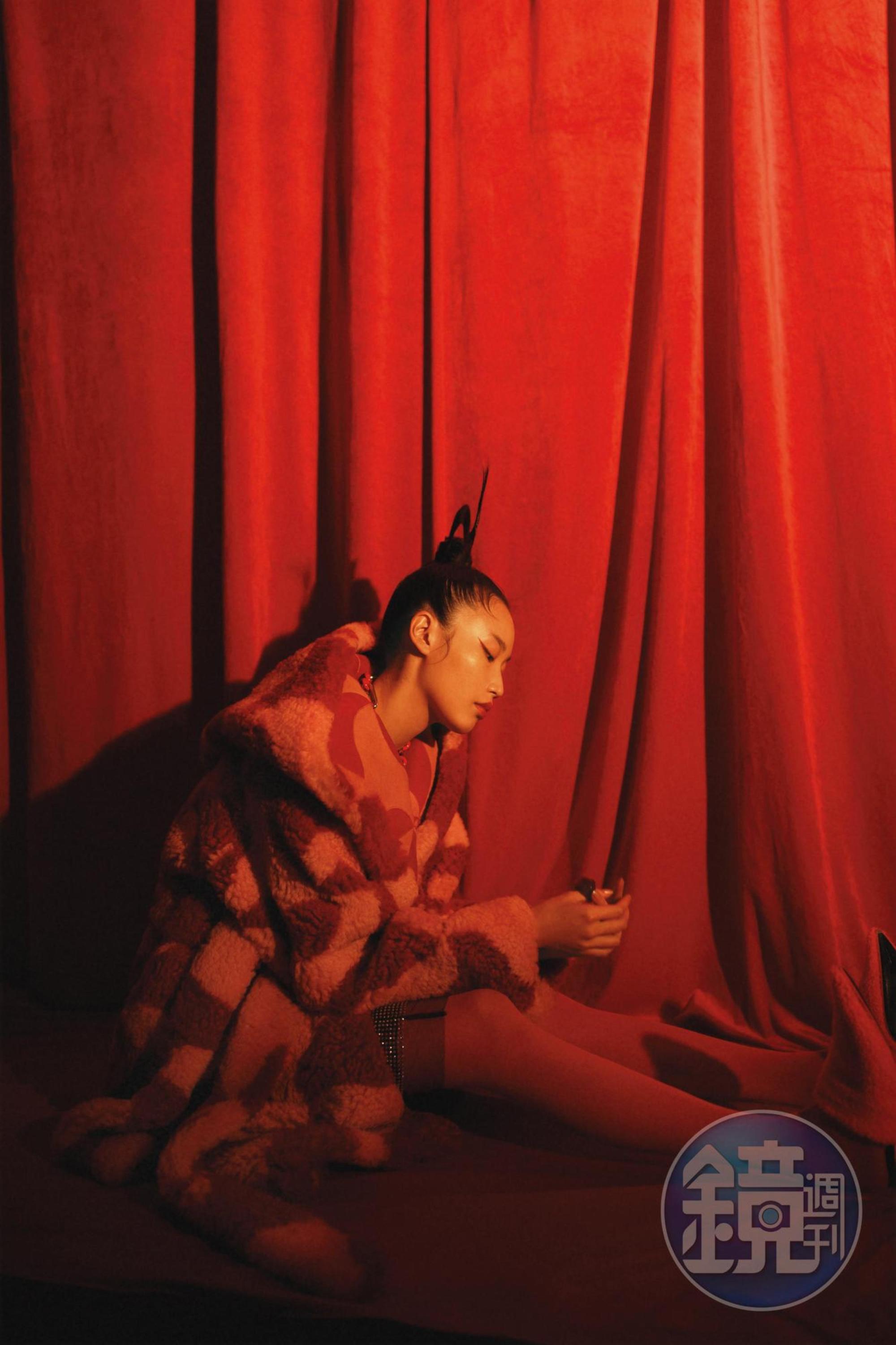 色紅色拼接剪羊毛大衣,NT$388,600,by Bottega Venata;黑色水晶綴飾及膝裙,價格店洽,by PRADA;橘色褲襪,價格店洽,by Valentino;橘色羔羊毛尖頭穆勒鞋,價格店洽,by LOEWE。