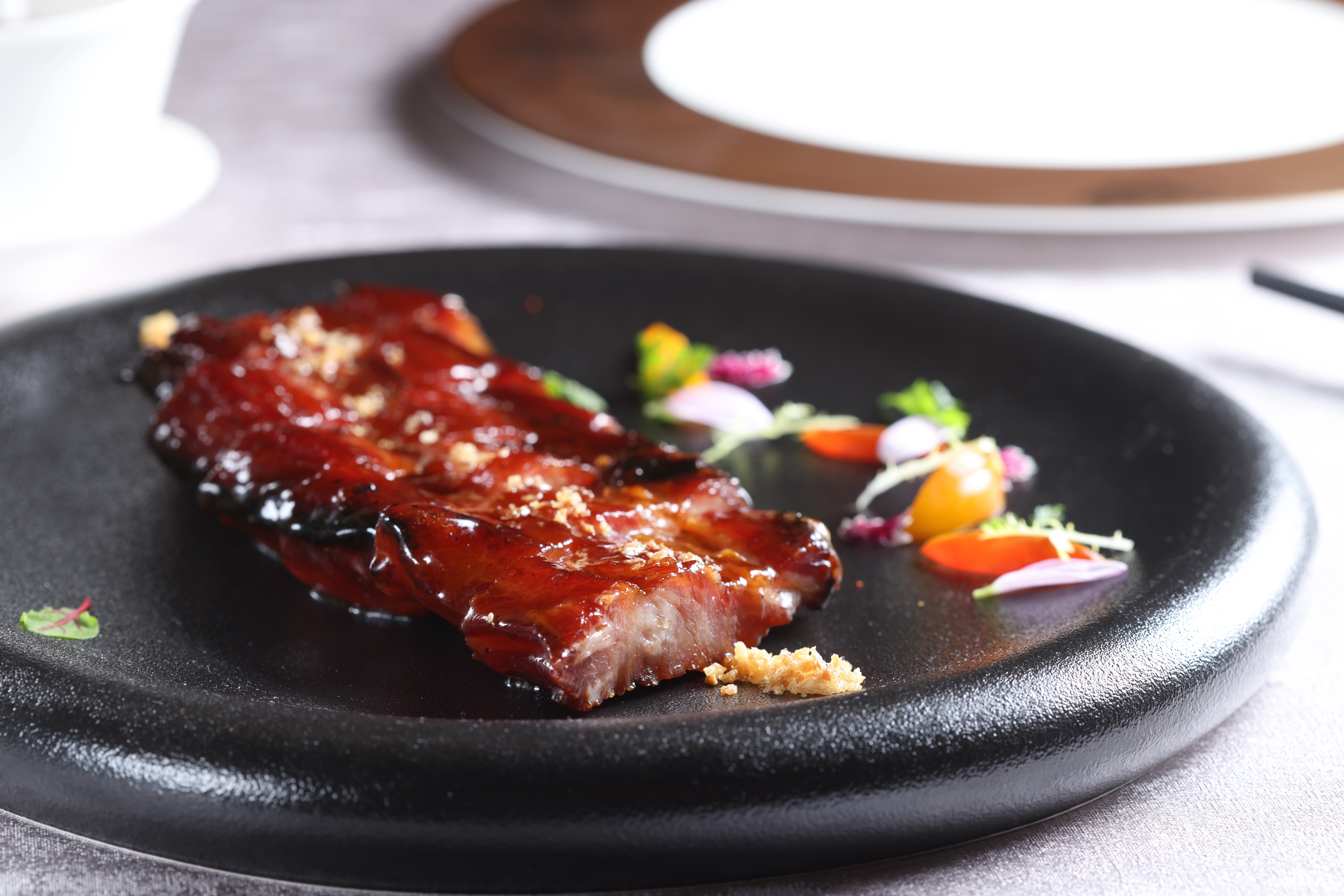 肥瘦均勻的「金蒜黑豚叉燒」，烤得微帶燶邊且多汁，再以蒜酥提香。（1,080元／份）