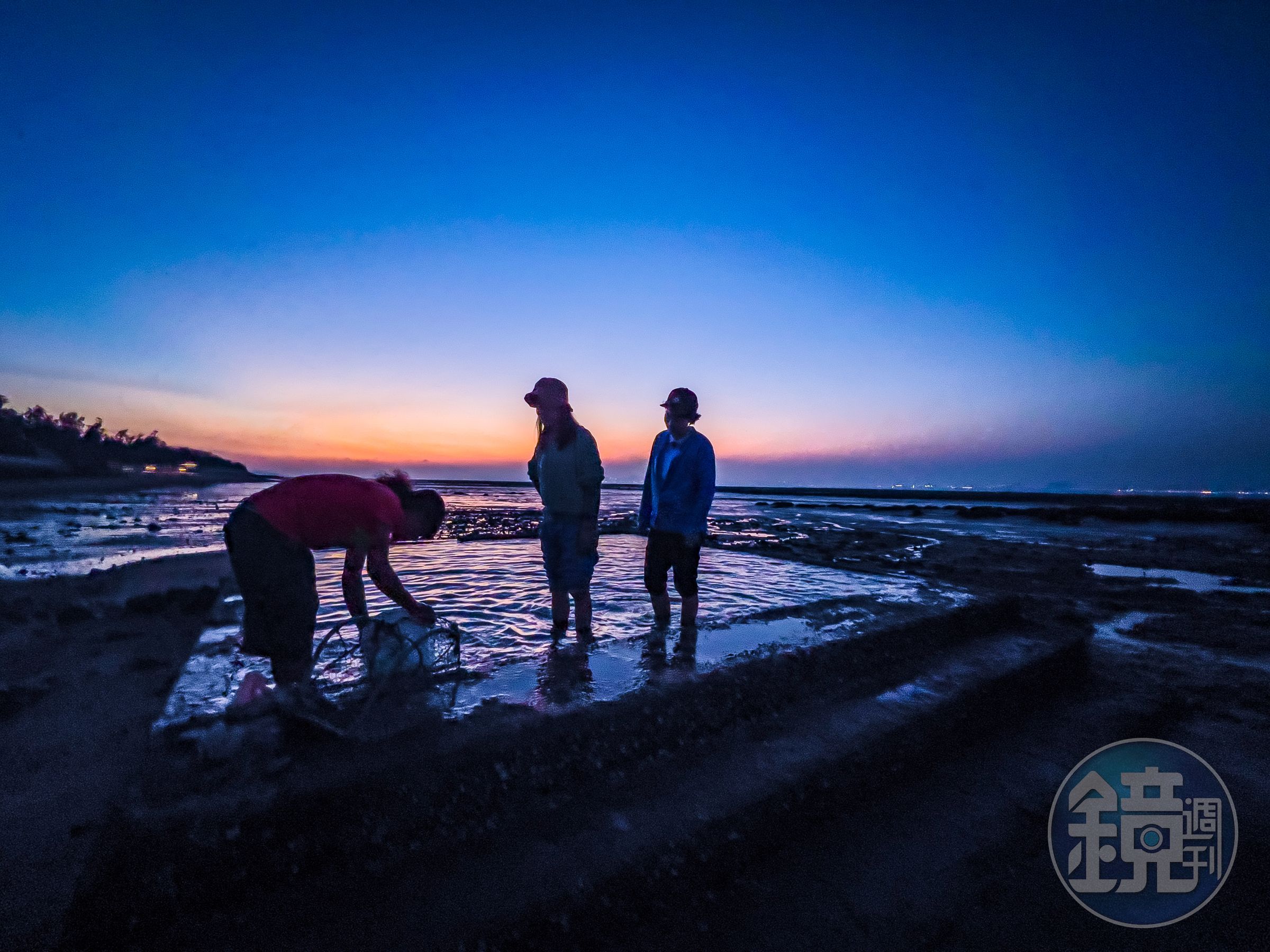 金門石蚵田採收之後在水池清理泥沙，背後伴隨的夕陽是一幅天然美景。