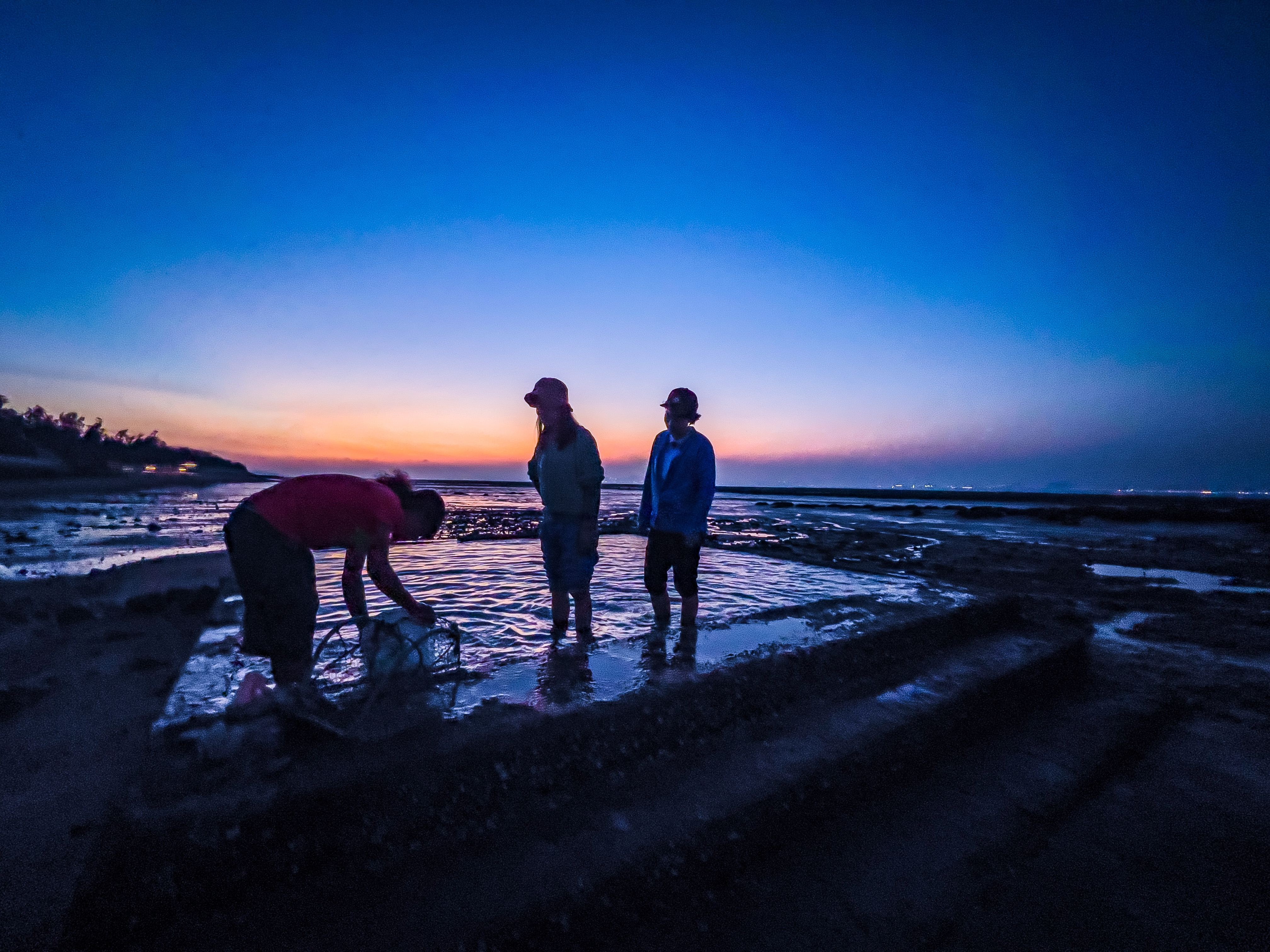 金門石蚵田採收之後在水池清理泥沙，背後伴隨的夕陽是一幅天然美景。