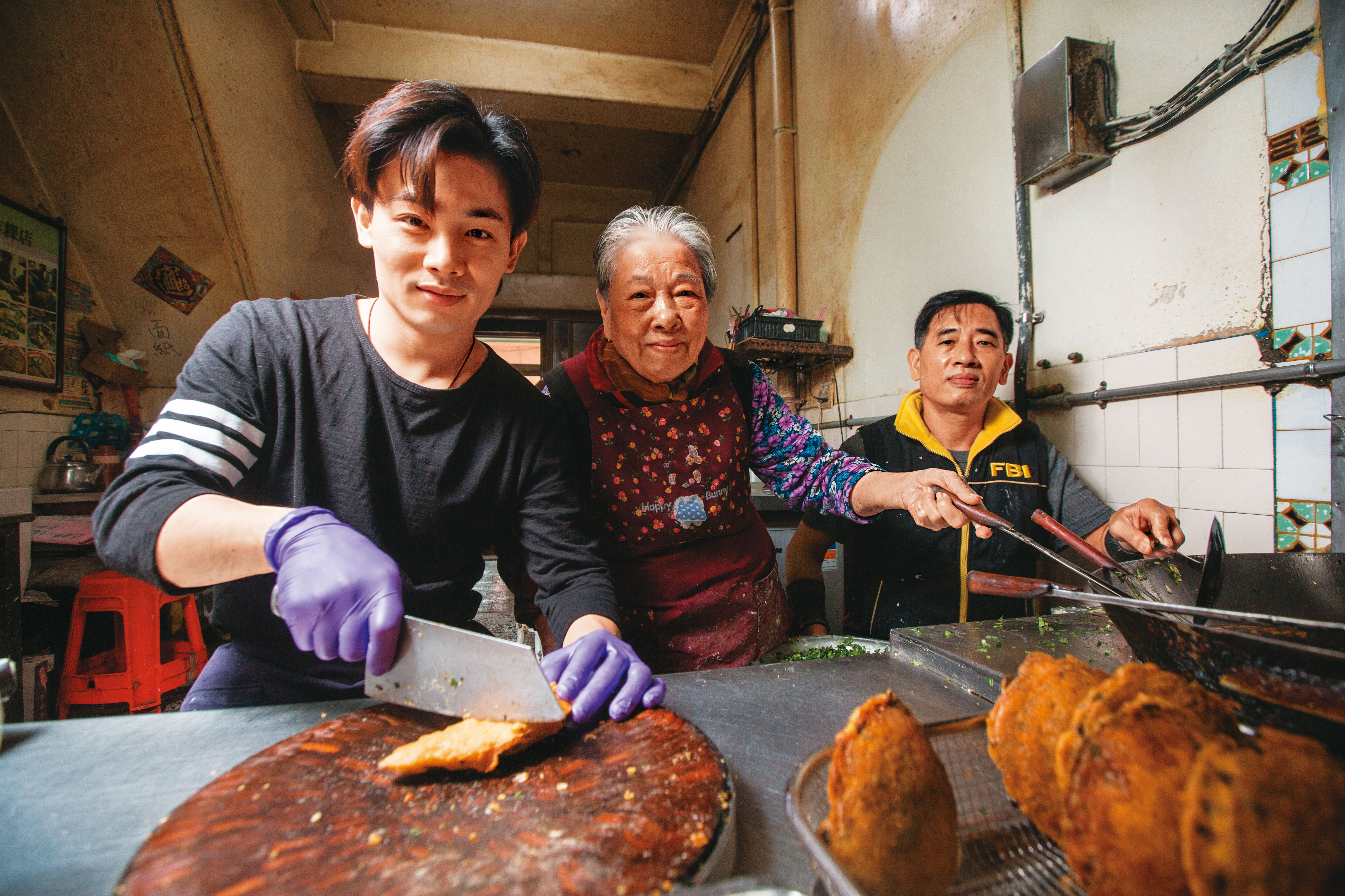 阿源炸粿創立至今已100年，現在由第二代林玉霞（中）與兒子許峰銓（右）、孫子許凱綸（左）一起經營。