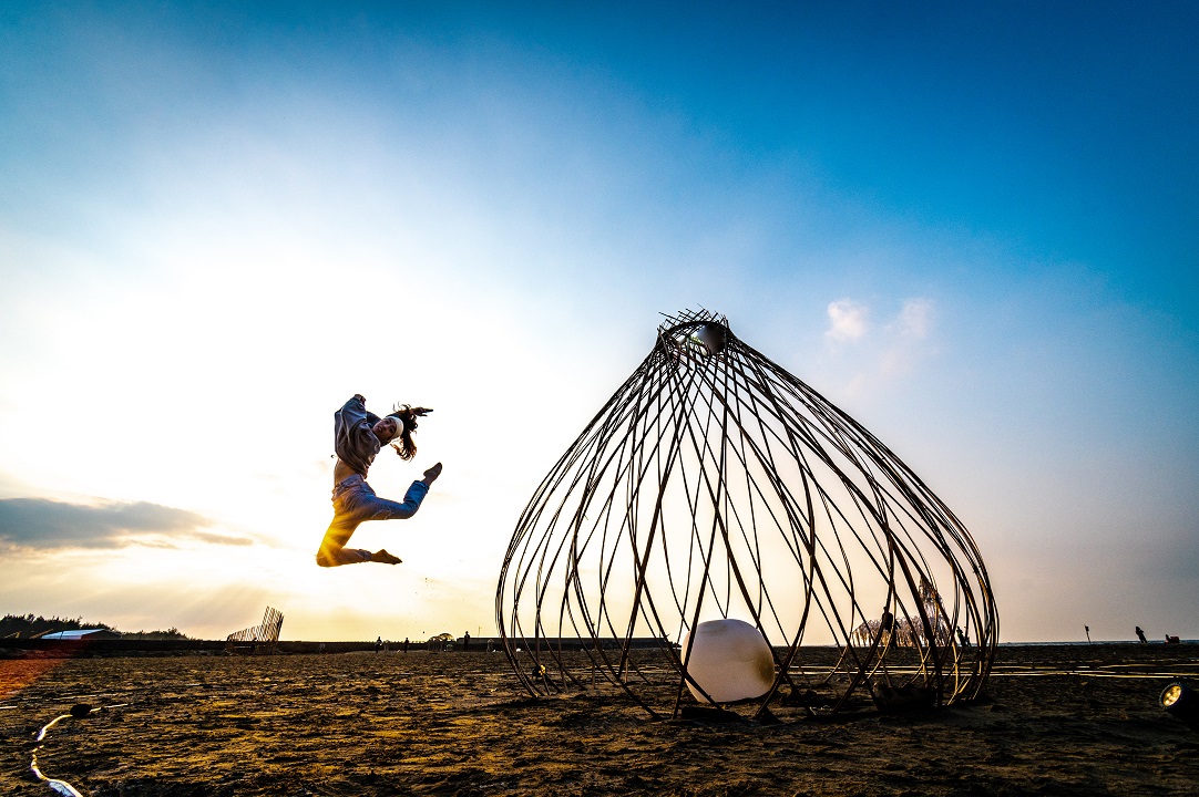 外觀像車城名產洋蔥一樣的作品《跟風· 起舞》，舞者剛好在沙灘上躍起。