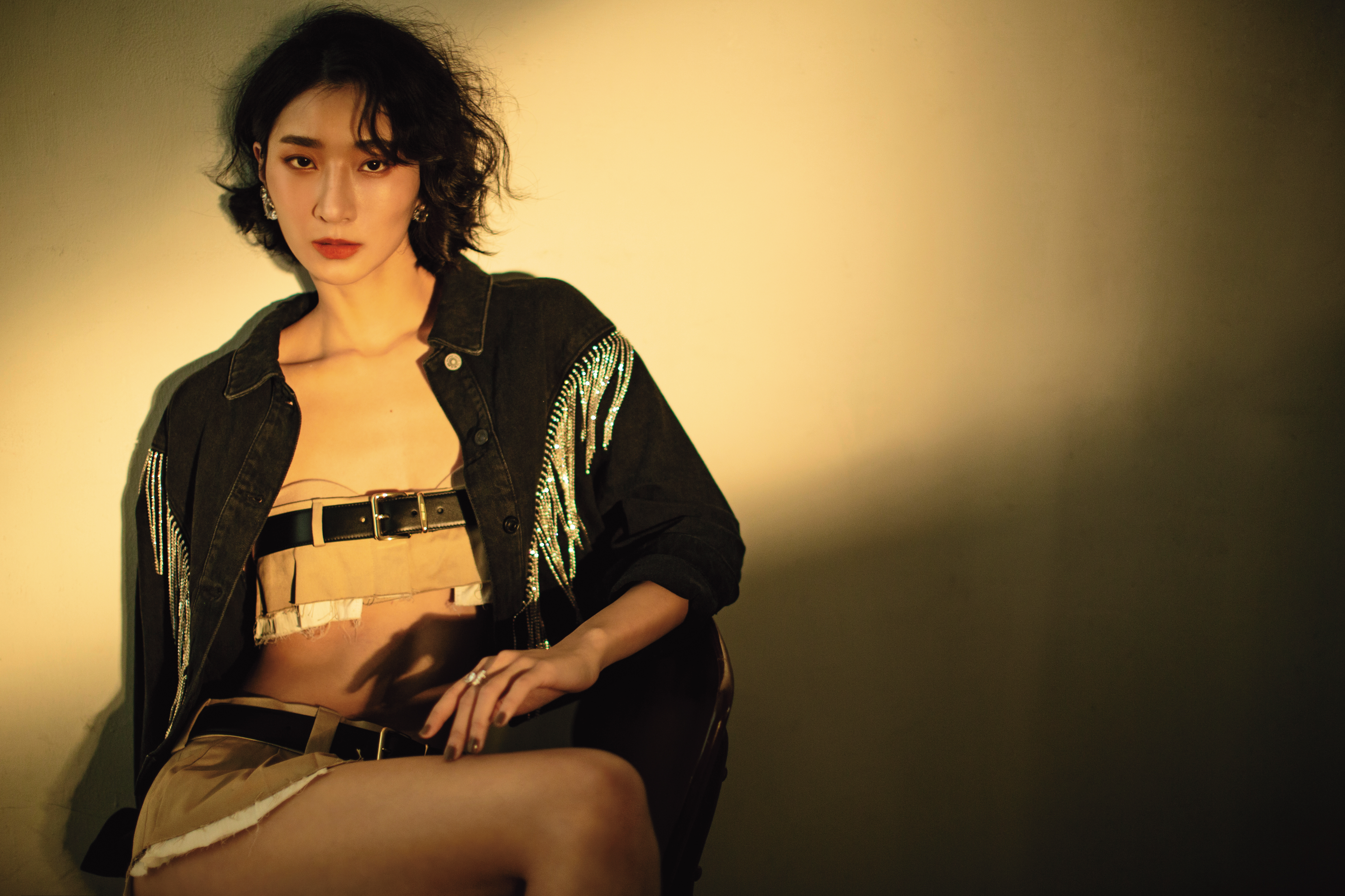 水晶流蘇短版牛仔外套 NT$10,100 by ALLSAINTS／細腰帶短版上衣 價格店洽 by MIU MIU／低腰繫帶迷你百褶裙 價格店洽 by MIU MIU／（左）夾式耳環套組（三個） NT$4,990 by SWAROVSKI／（右）單顆夾式耳環 NT$2,490 by SWAROVSKI／戒指 NT$8,490 by SWAROVSKI