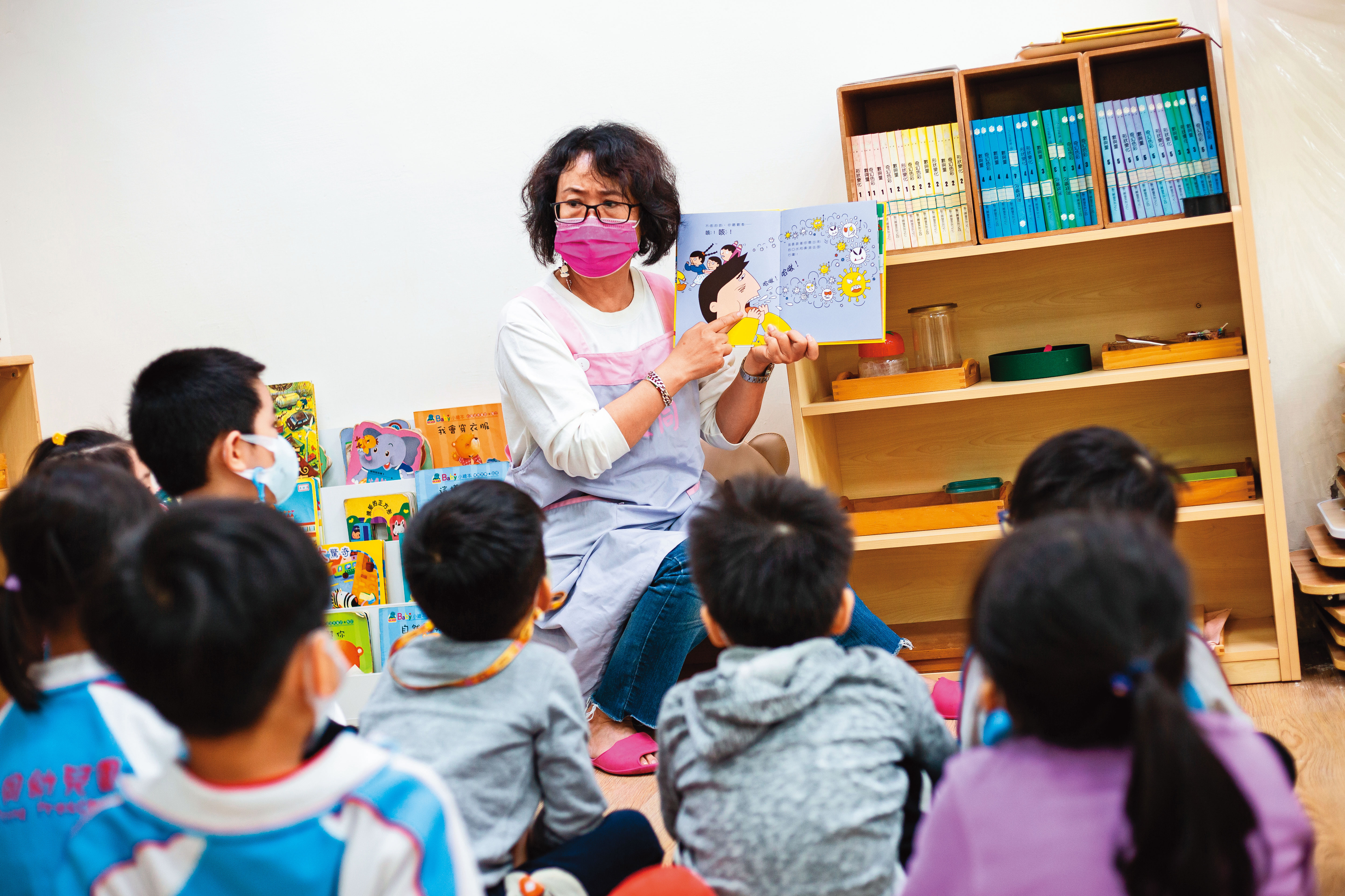 幼兒園老師透過繪本描述病毒的傳染途徑。