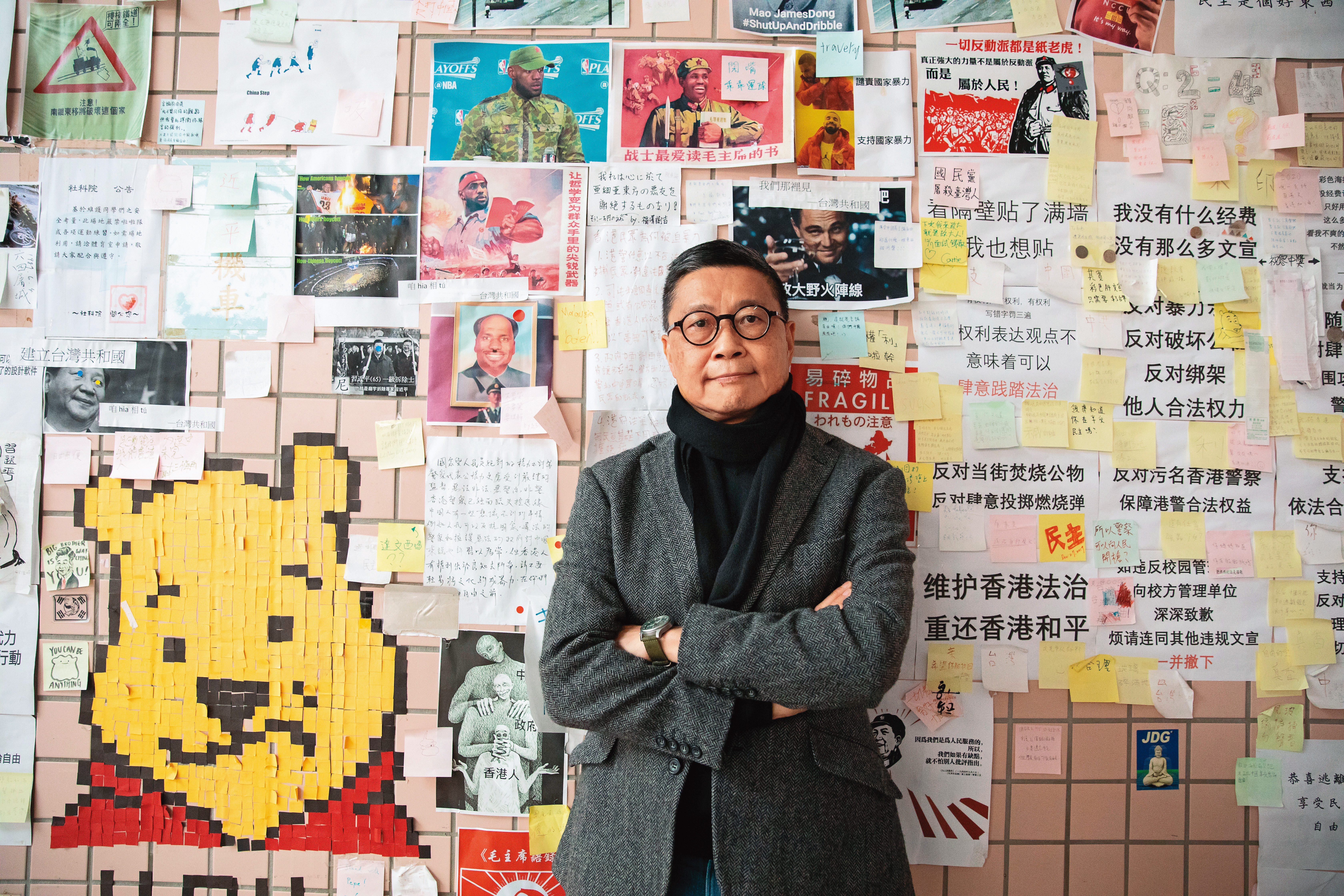 接受採訪這天，陳健民領我們到政大連儂牆前，他身後幾張簡體字樣，疑似是大陸學生對台港學生的嗆聲。