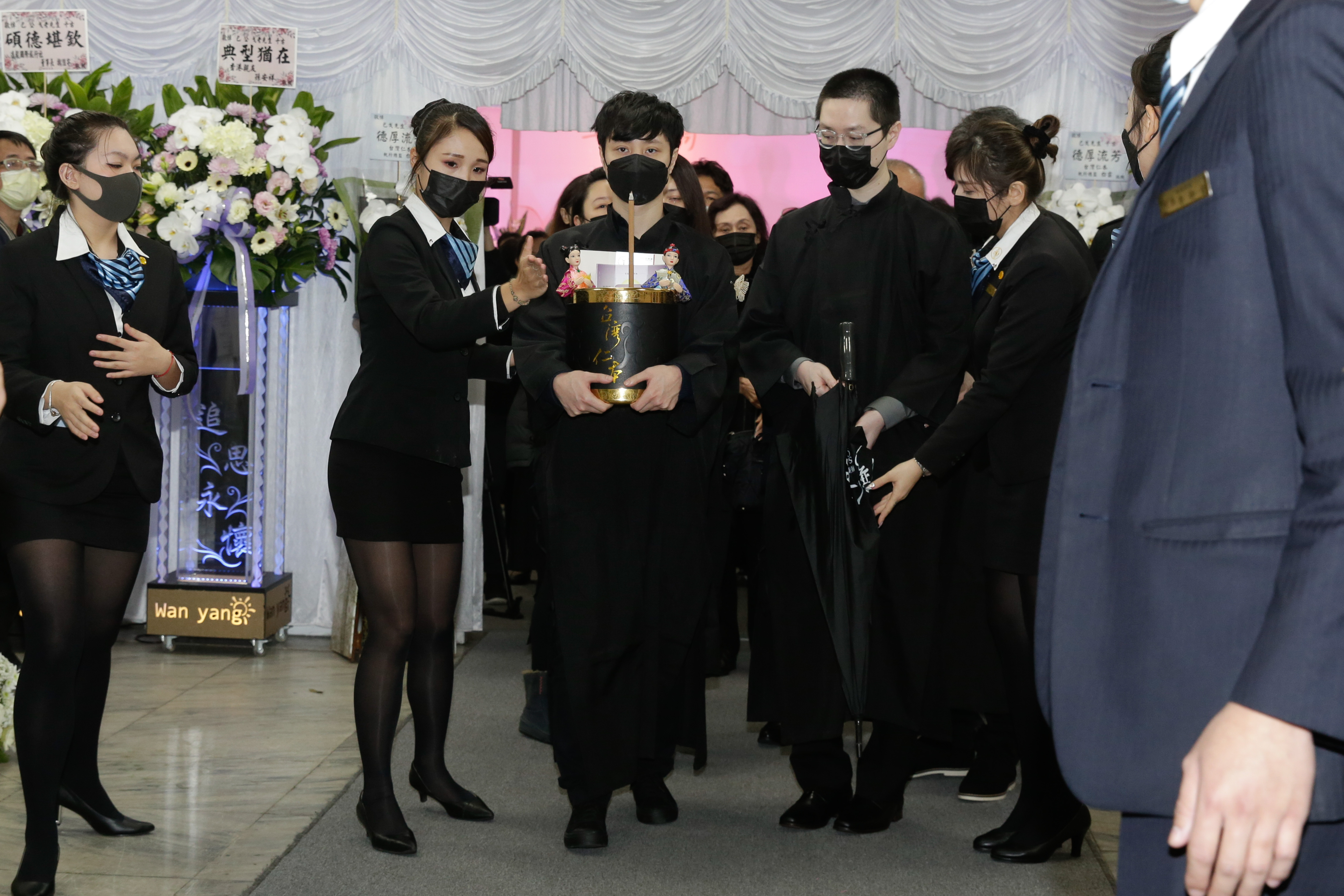 巴戈兒子手捧靈位，陪伴父親走完最後一程。