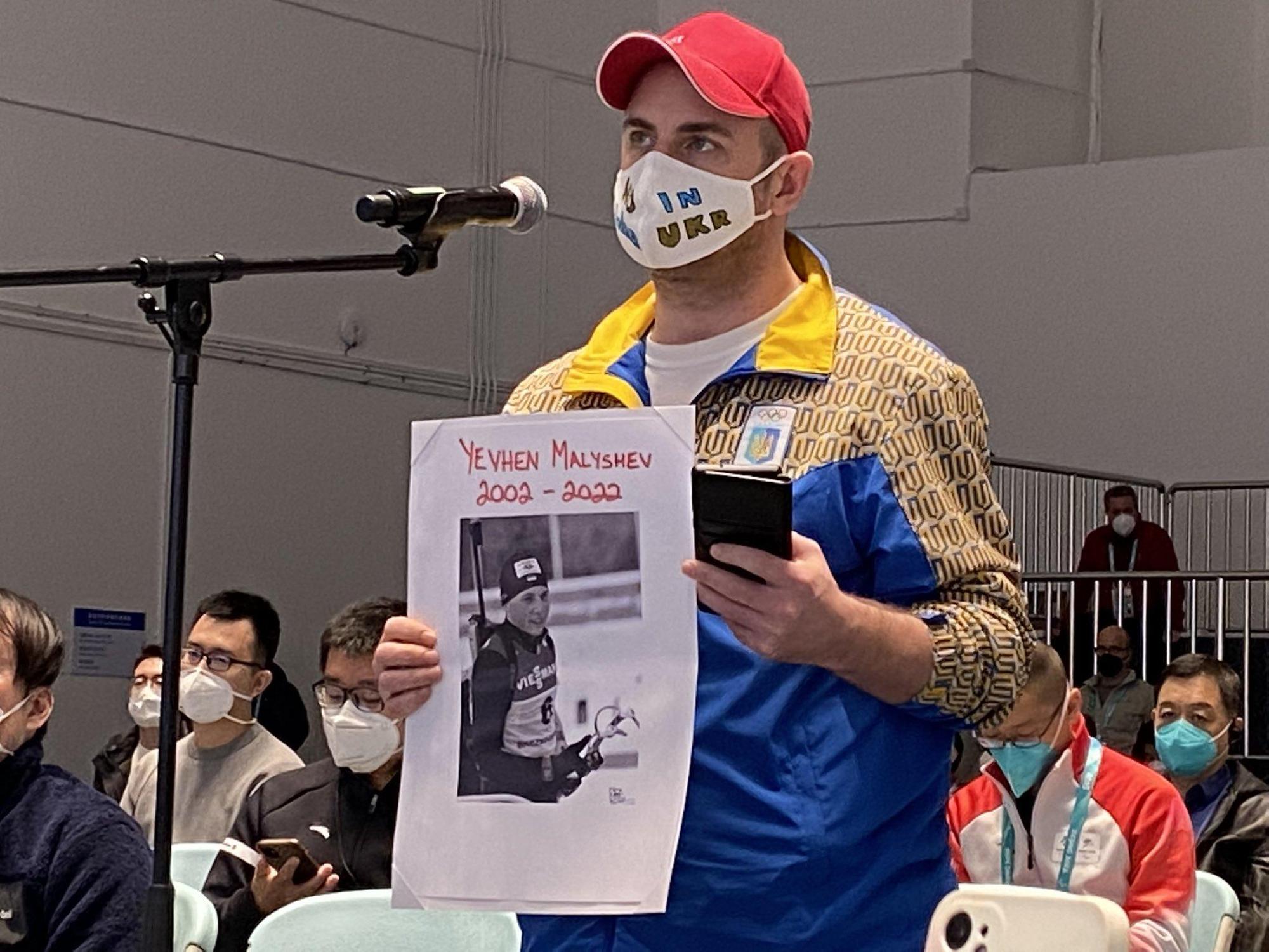 烏克蘭記者拿出在戰爭中罹難的運動員照片,抗議IPC的決定。(翻攝自推特@Devin_Heroux)