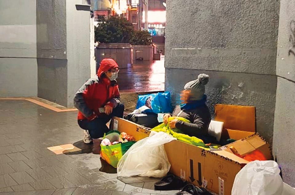 今年2月底,寒流來襲,張獻忠(左)在街頭發送暖暖包給無家者。他說:「這是基本sense,冬天來時就該先訂好(保暖物資)。」(張獻忠提供)